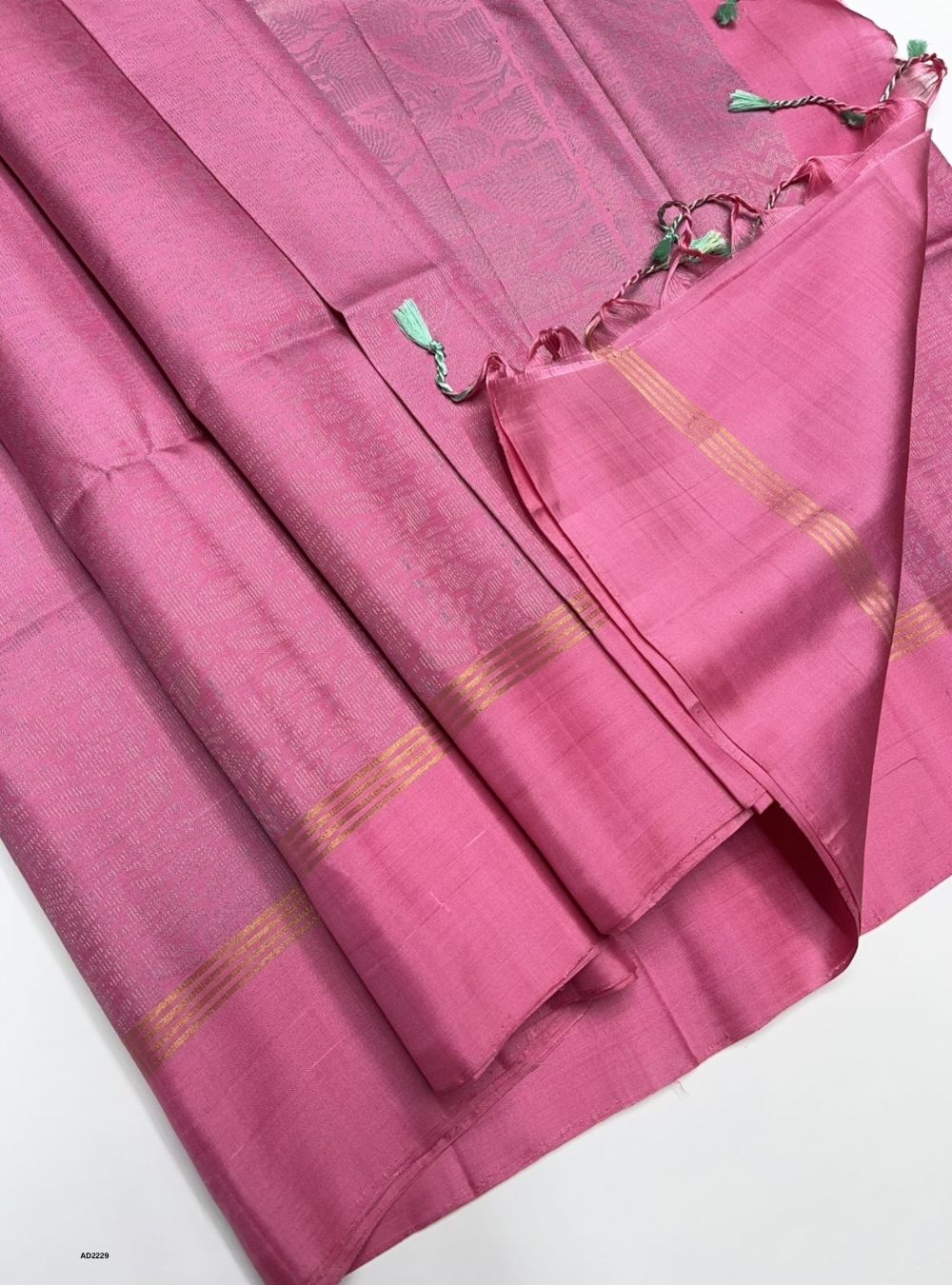 Pink saree with gold stripes on a white background