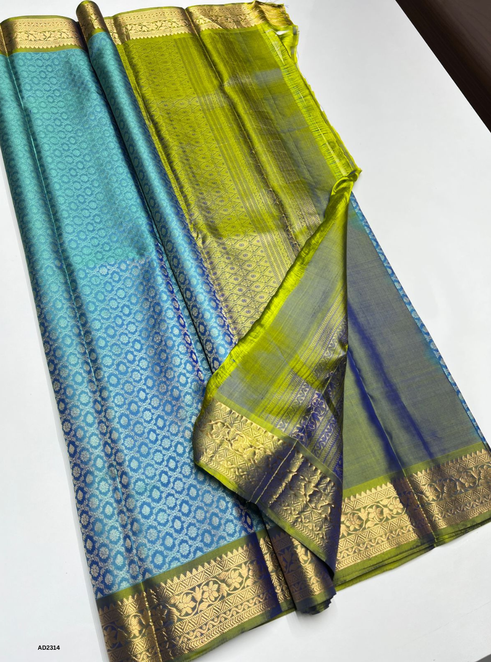 Blue and green saree with gold border on a white background