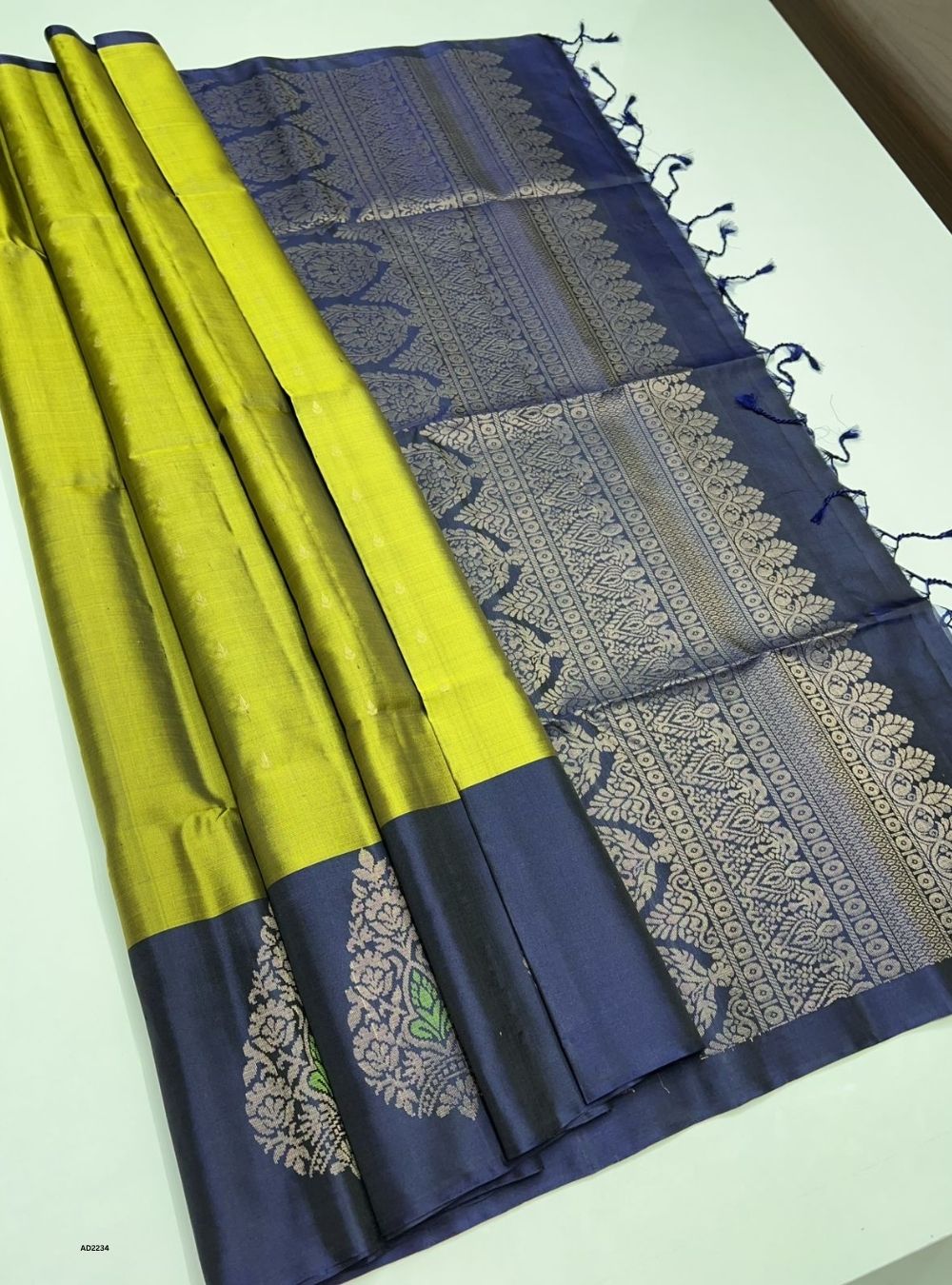 Blue and lime green saree with intricate patterns on a white background