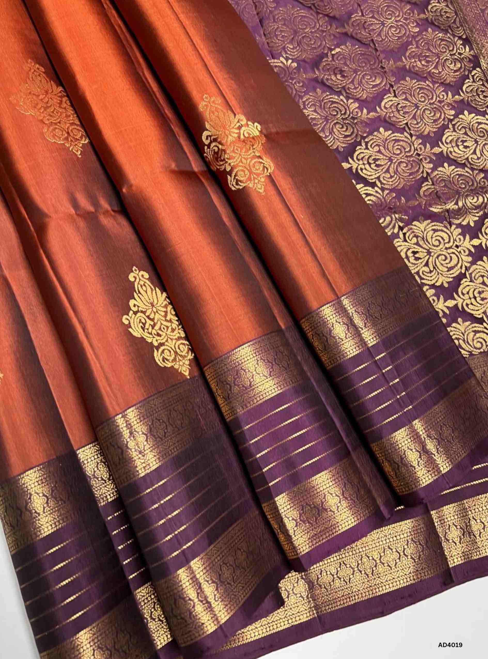 The Brown & Plum Kanchi Border Soft Silk Saree is a heritage handwoven creation that radiates festive brilliance and cultural richness. The earthy brown shade symbolizes grounded elegance, while the regal plum tone adds depth, prosperity, and sophistication. The grand Kanchi border, adorned with temple‑inspired motifs in pure gold zari, elevates its heritage appeal. The shimmering pallu completes the ensemble, making it perfect for weddings, temple ceremonies, and cultural celebrations. This saree embodies