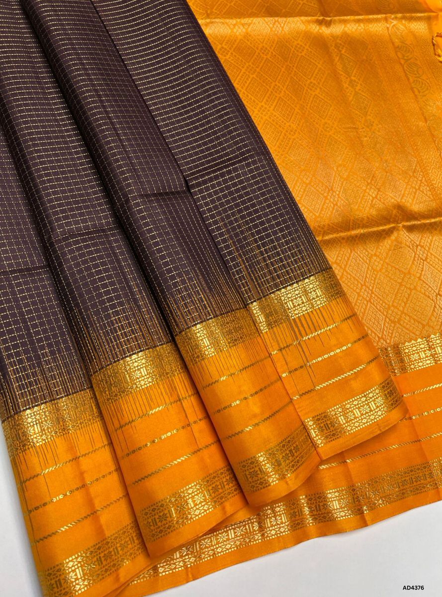 The Coffee Brown & Mango Yellow Checkered Retta Pet Soft Silk Saree is a radiant handwoven creation that embodies festive charm and cultural grandeur. The coffee brown shade conveys devotion, warmth, and heritage depth, while the mango yellow checks symbolize joy, prosperity, and celebratory brilliance. Enhanced with pure gold zari borders and a lustrous drape, this saree is perfect for weddings, temple ceremonies, and festive occasions. A timeless masterpiece, it blends earthy richness with vibrant dual‑to