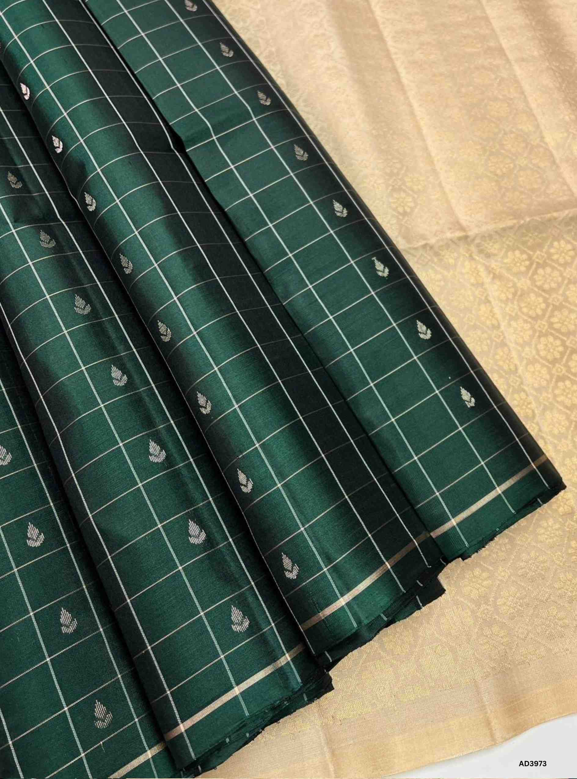 The Dark Green & Cream Checkered Bhutta Soft Silk Saree is a refined handwoven creation that celebrates heritage weaving with a timeless dual‑tone palette. The deep dark green shade radiates prosperity and cultural depth, while the cream tone adds softness and understated elegance. The checkered bhutta weave, adorned with delicate motifs, enhances the saree’s artistry, while zari highlights on the border and pallu lend a shimmering appeal. Perfect for weddings, temple ceremonies, and festive occasions, this