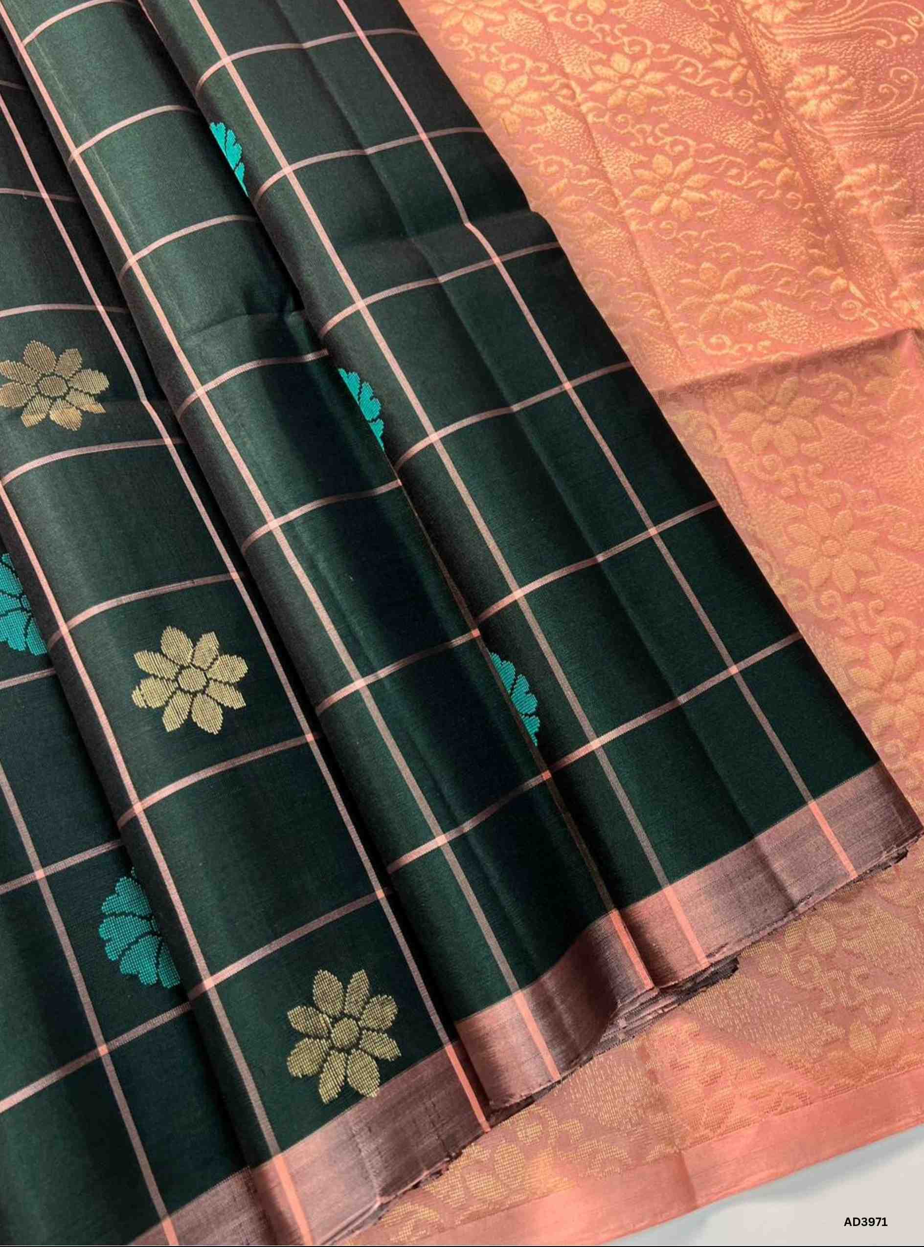 The Dark Green & Peach Checkered Bhutta Soft Silk Saree is a captivating handwoven creation that celebrates festive grandeur with heritage weaving. The deep dark green shade radiates prosperity and cultural depth, while the peach tone adds softness and celebratory warmth. The checkered bhutta weave, adorned with delicate motifs, enhances the saree’s artistry, while zari highlights on the border and pallu lend a shimmering appeal. Perfect for weddings, temple ceremonies, and cultural gatherings, this saree e