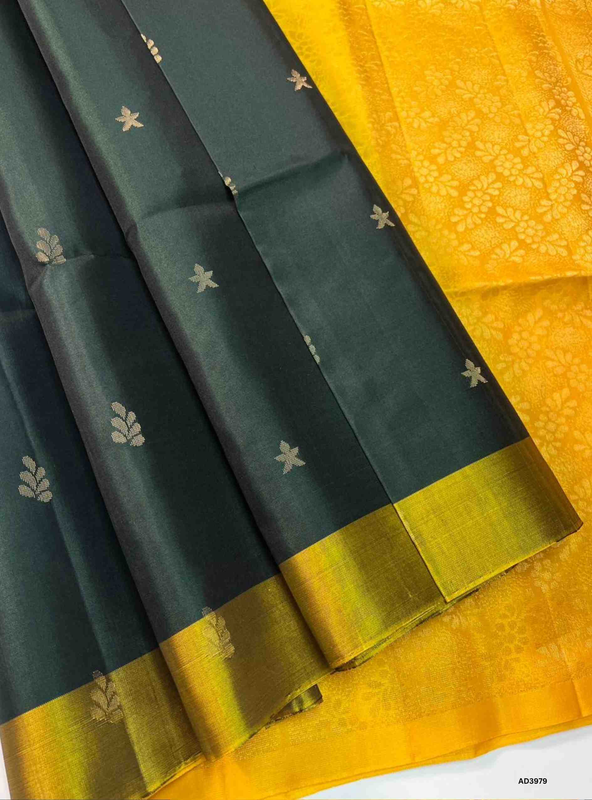 The Dark Green & Yellow Bhutta Soft Silk Saree is a radiant handwoven creation that celebrates festive grandeur with a vibrant dual‑tone palette. The deep dark green shade symbolizes prosperity and cultural richness, while the bright yellow adds auspicious brilliance and warmth. The bhutta weave, adorned with intricate motifs, enhances the saree’s artistry, while zari highlights on the border and pallu lend a shimmering appeal. Perfect for weddings, temple ceremonies, and cultural gatherings, this saree emb