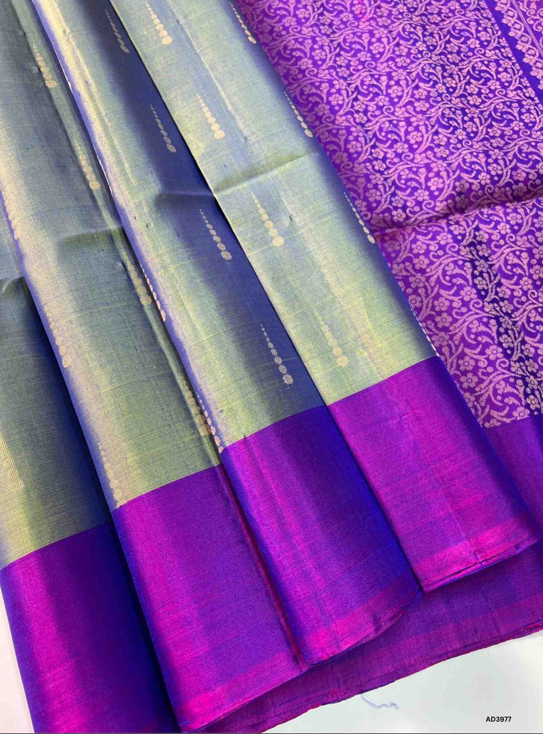 The Dual Tone Green & Purple Bhutta Soft Silk Saree is a striking handwoven creation that celebrates festive grandeur with a regal dual‑tone palette. The refreshing green shade radiates prosperity and cultural charm, while the deep purple adds richness and sophistication. The bhutta weave, adorned with intricate motifs, enhances the saree’s artistry, while zari highlights on the border and pallu lend a shimmering appeal. Perfect for weddings, temple ceremonies, and cultural gatherings, this saree embodies S