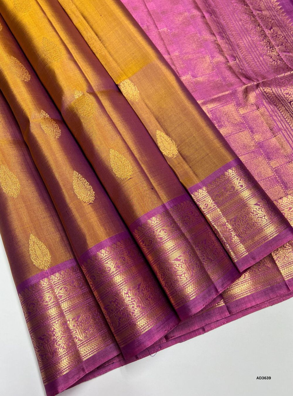 The Golden Brown & Pink Soft Silk Saree is a radiant handwoven creation featuring a warm golden brown body enriched with shimmering zari. Its vibrant pink border and pallu showcase the intricate Kachi style border, adding grandeur and traditional charm. Perfect for weddings, festive occasions, and cultural gatherings, this saree blends earthy richness with timeless Kachi craftsmanship.