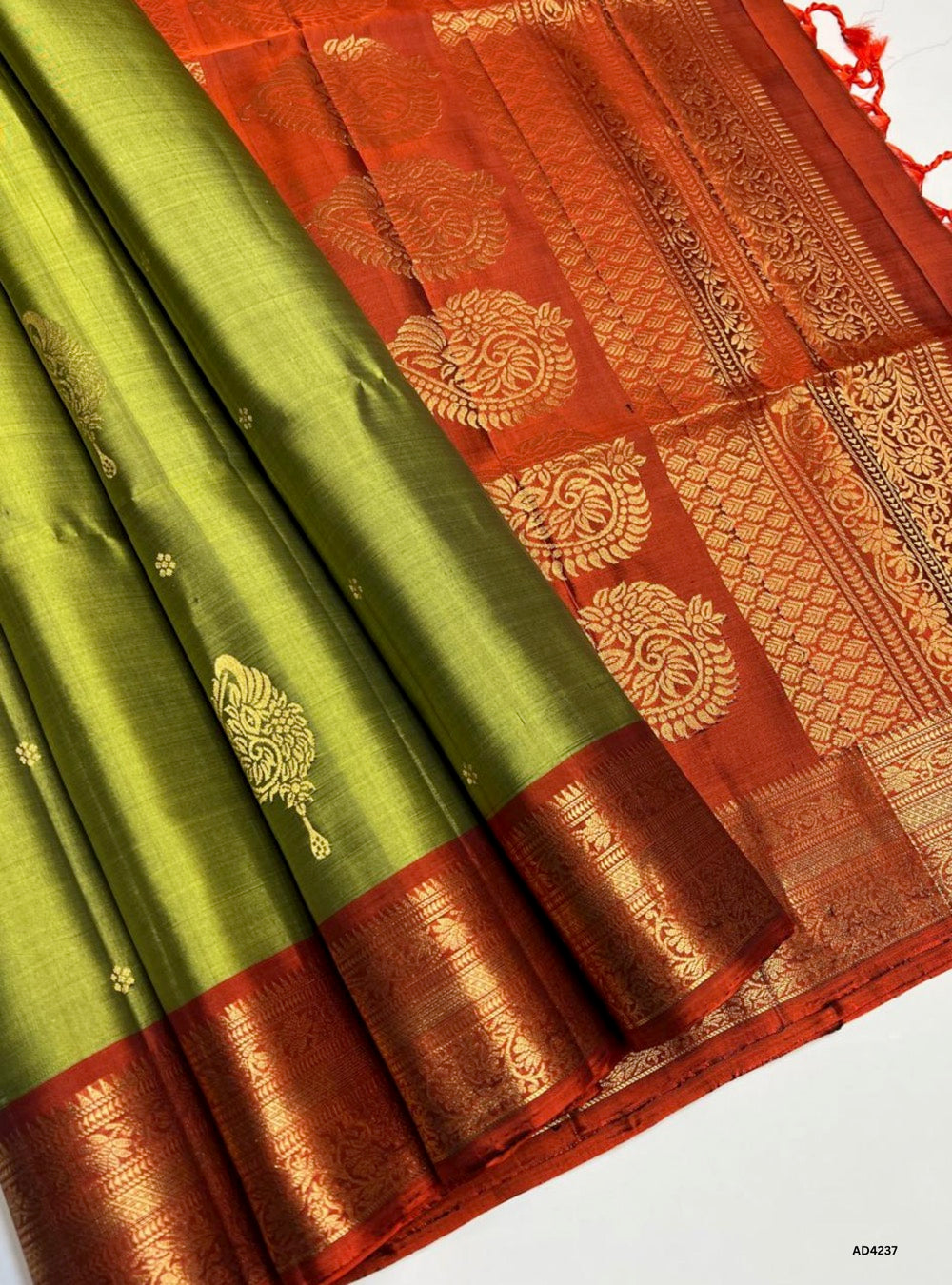 The Green & Rust Kanchi Border Soft Silk Saree is a radiant handwoven creation that celebrates festive grandeur and cultural heritage. The green shade symbolizes prosperity, devotion, and auspicious beginnings, while the rust tone conveys warmth, energy, and celebratory charm. Together, they form a striking palette enriched with temple‑inspired Kanchi borders and pure gold zari detailing. Perfect for weddings, temple ceremonies, and festive gatherings, this saree reflects the artistry of Kanchipuram weavin