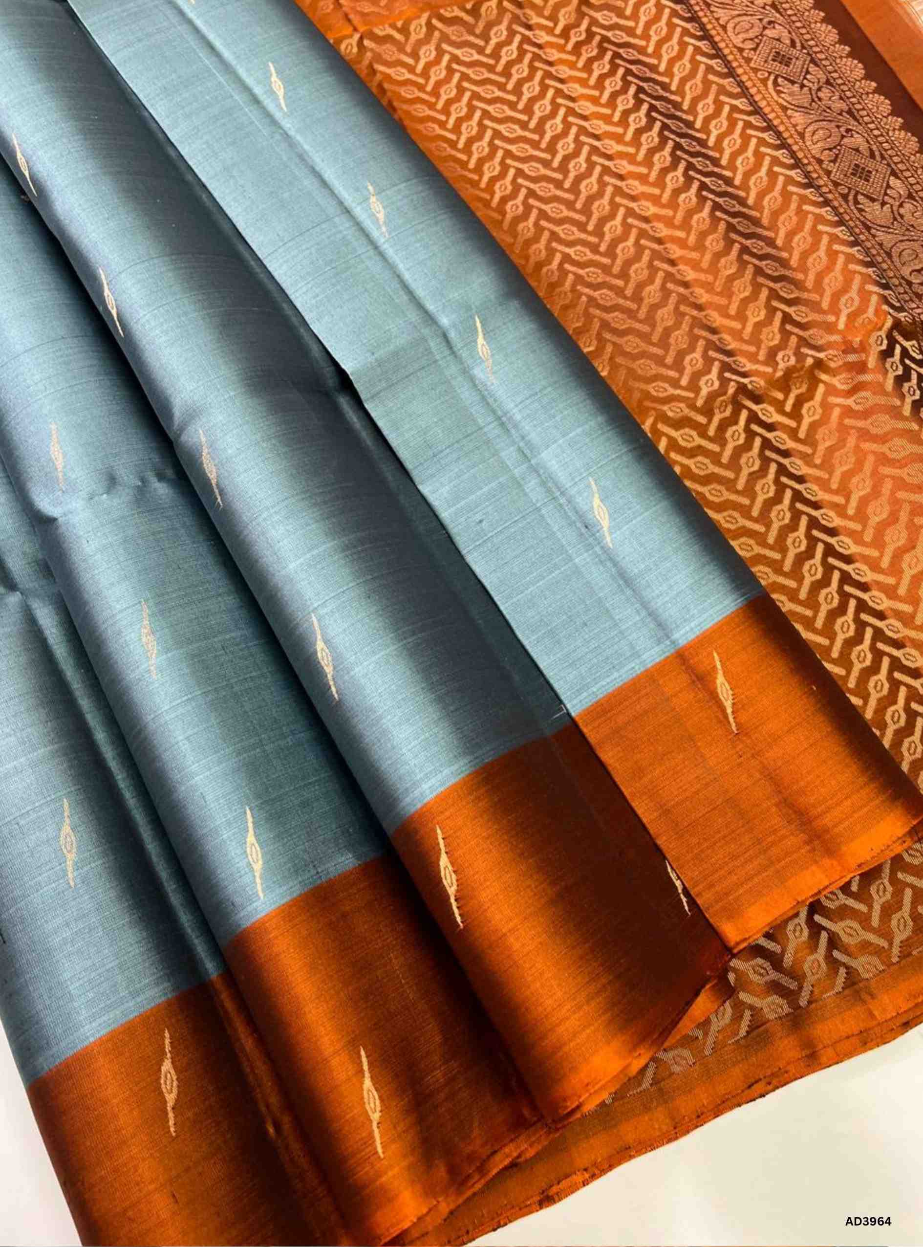 The Grey & Rust Orange Bhutta Soft Silk Saree is a refined handwoven creation that celebrates earthy elegance with festive charm. The subtle grey shade radiates calm sophistication, while the rust orange adds warmth and cultural vibrancy. The bhutta weave, adorned with intricate motifs, enhances the saree’s artistry, while zari highlights on the border and pallu lend a shimmering appeal. Perfect for weddings, temple ceremonies, and cultural gatherings, this saree embodies South Indian weaving tradition with