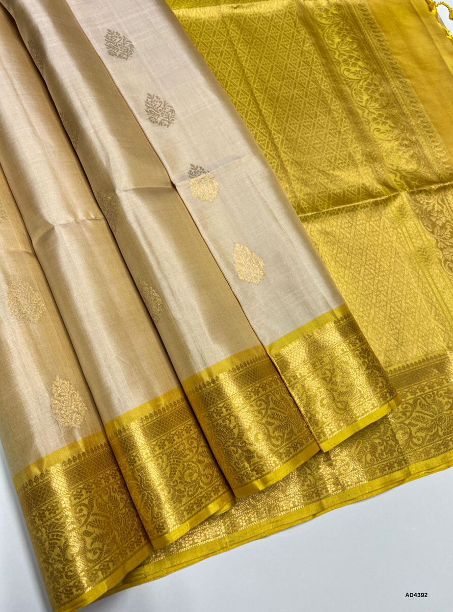 The Ivory & Yellow Kanchi Border Soft Silk Saree is a graceful handwoven creation that radiates festive charm and cultural richness. The ivory shade conveys purity, calmness, and timeless elegance, while the vibrant yellow adds auspicious brilliance and celebratory warmth. The temple‑inspired Kanchi border enriched with pure gold zari elevates its grandeur, making it perfect for weddings, temple ceremonies, and festive occasions. A timeless piece of artistry, it blends pastel serenity with radiant vibrance