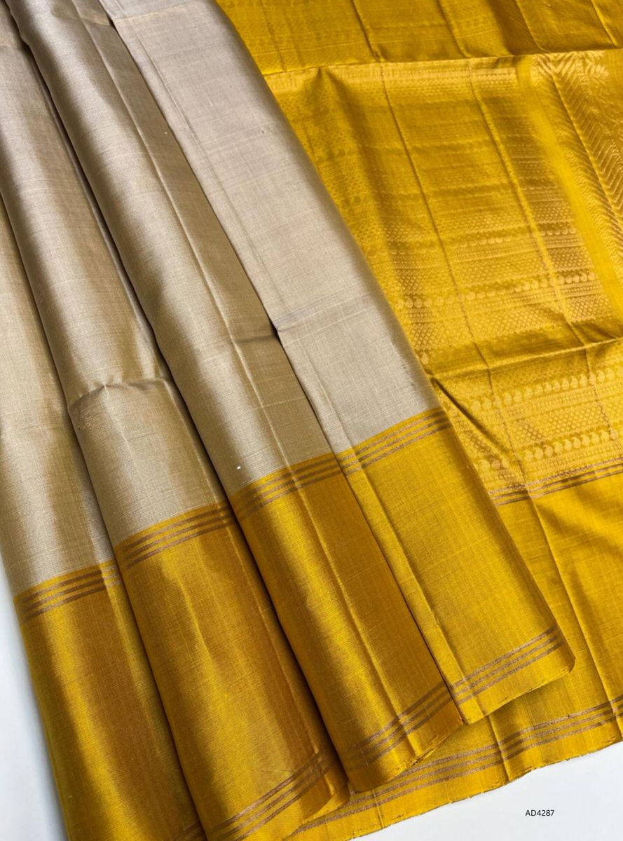The Ivory & Yellow Soft Silk Saree Bhutta is a graceful handwoven creation that radiates festive charm and cultural elegance. The ivory shade conveys purity, calmness, and timeless sophistication, while the vibrant yellow adds auspicious brilliance and celebratory warmth. Enhanced with pure gold zari borders and Bhutta motifs, this saree is perfect for weddings, temple ceremonies, and festive occasions. A timeless piece of artistry, it blends radiant brilliance with serene elegance in traditional South Indi