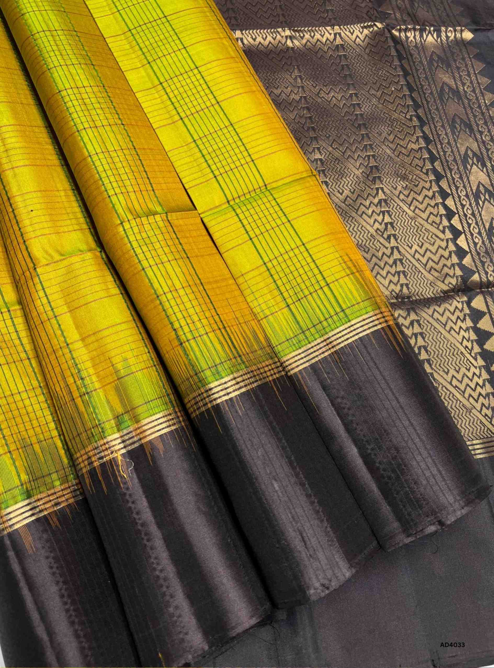 The Mehandi Green & Coffee Brown Checkered Soft Silk Saree is a graceful handwoven creation that radiates festive charm and cultural heritage. The earthy mehandi green shade symbolizes prosperity and tradition, while the deep coffee brown adds grounded elegance and richness. The checkered weave enhances its geometric appeal, while the Retta Pet border, a hallmark of Kanchipuram artistry, features temple‑inspired double lines in pure gold zari. Perfect for weddings, temple ceremonies, and festive occasions,