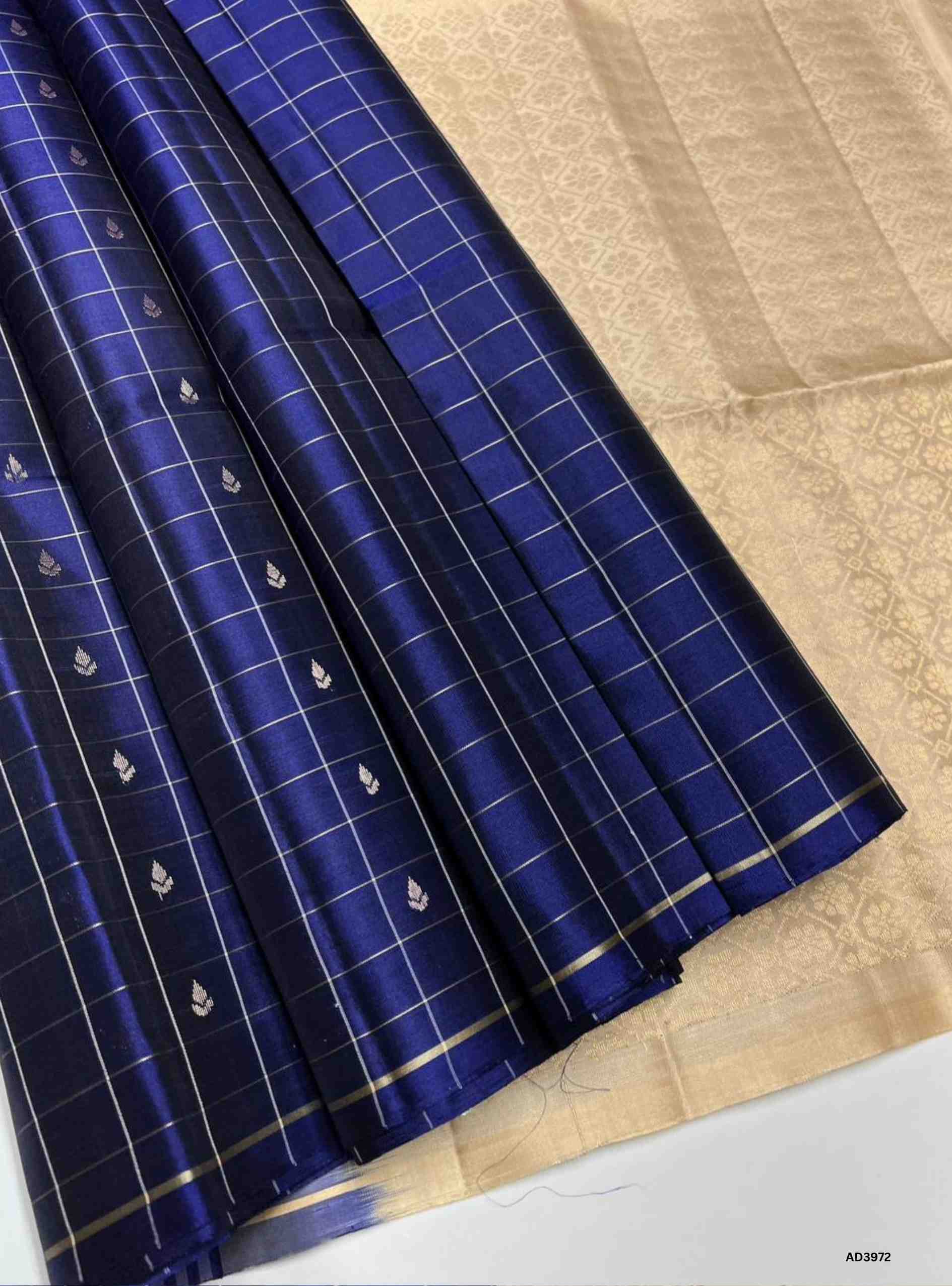 The Navy Blue & Cream Checkered Bhutta Soft Silk Saree is a timeless handwoven creation that celebrates heritage weaving with a graceful dual‑tone palette. The deep navy blue shade radiates regal sophistication, while the cream tone adds softness and understated charm. The checkered bhutta weave, adorned with delicate motifs, enhances the saree’s artistry, while zari highlights on the border and pallu lend a shimmering appeal. Perfect for weddings, temple ceremonies, and festive occasions, this saree embodi