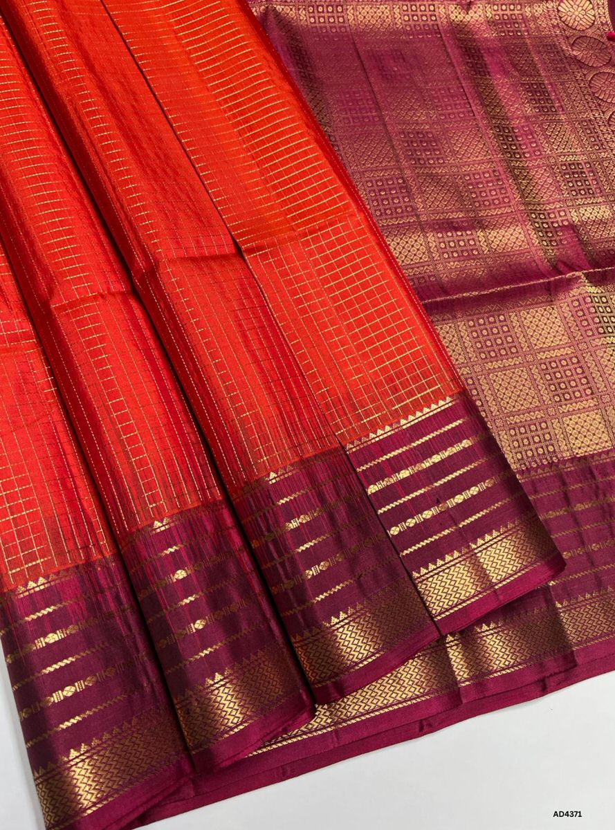 The Orange & Maroon Checkered Retta Pet Soft Silk Saree is a radiant handwoven creation that embodies festive charm and cultural richness. The orange shade conveys joy, devotion, and celebratory vibrance, while the maroon checks symbolize heritage depth, auspiciousness, and regal elegance. Enhanced with pure gold zari borders and a lustrous drape, this saree is perfect for weddings, temple ceremonies, and festive occasions. A timeless masterpiece, it blends vibrant dual tones with the traditional Retta Pet