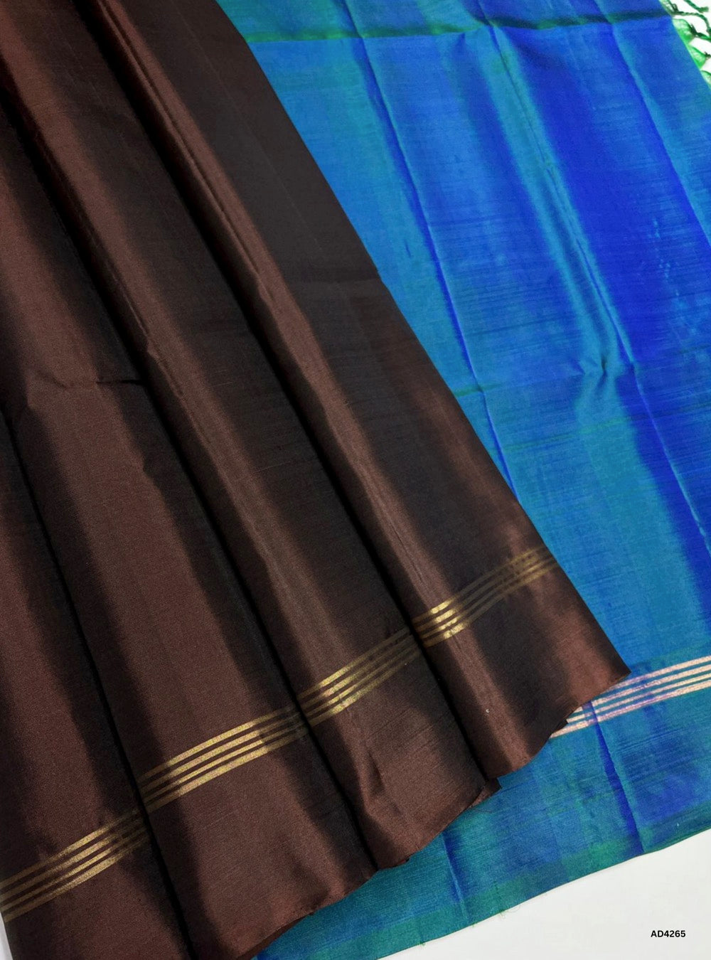 The Peacock Blue & Brown Contrast Plain Soft Silk Saree is a refined handwoven creation that radiates elegance and cultural charm. The peacock blue shade symbolizes prosperity, devotion, and timeless vibrance, while the brown contrast adds grounded richness and sophistication. Enhanced with subtle zari borders and a lustrous drape, this saree is perfect for weddings, temple ceremonies, and festive occasions. A versatile piece of artistry, it blends jewel‑tone brilliance with earthy contrast in traditional S