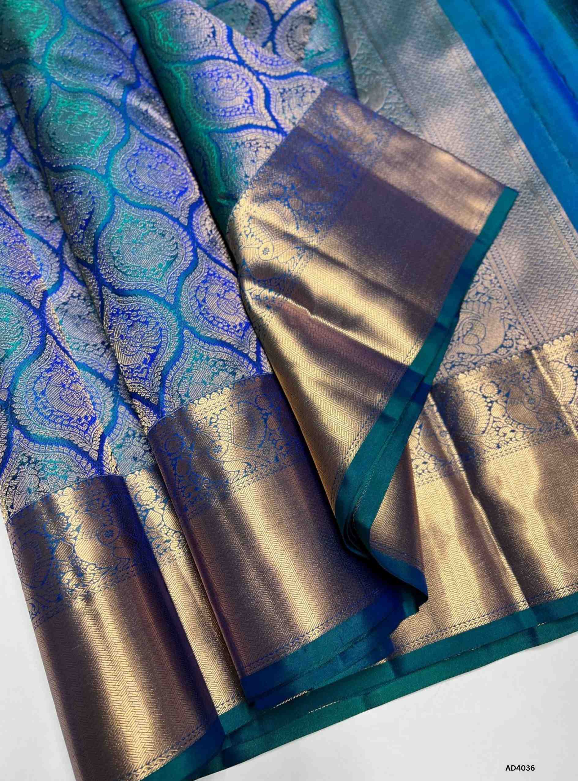 The Peacock Blue Kanjeevaram Bridal Soft Silk Saree is a majestic handwoven masterpiece crafted for weddings and auspicious occasions. The regal peacock blue shade symbolizes prosperity, joy, and auspicious brilliance, making it a timeless bridal choice. Its lustrous drape is enriched with heavy gold zari, temple‑inspired borders, and a grand pallu featuring motifs of peacocks, lotuses, and traditional geometric artistry. This saree embodies the heritage of Kanchipuram weaving, combining elegance with cultu