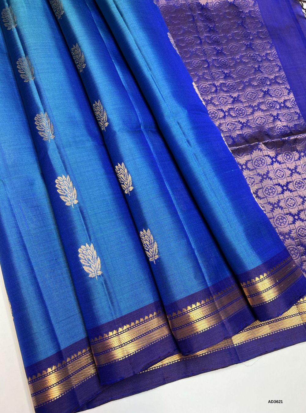 The Peacock Blue & Purple Soft Silk Saree is a majestic handwoven creation featuring a radiant peacock blue body enriched with shimmering zari. Its regal purple border and pallu showcase the intricate Kanchi style border, adding grandeur and traditional charm. Perfect for weddings, festive occasions, and cultural gatherings, this saree blends vibrant brilliance with timeless Kanchi craftsmanship