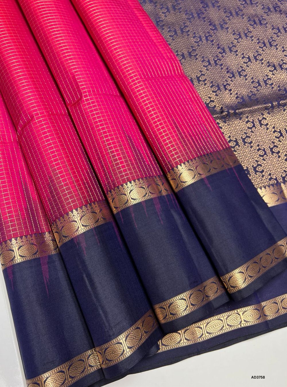 The Raspberry Pink & Ink Blue Retta Pet Saree is a striking handwoven creation featuring the double-line checks pattern (Retta Pet), a hallmark of South Indian weaving heritage. The lively raspberry pink body is adorned with zari checks, while the deep ink blue border adds richness and contrast. Perfect for weddings, temple ceremonies, and festive occasions, this saree embodies cultural tradition with a bold, timeless appeal