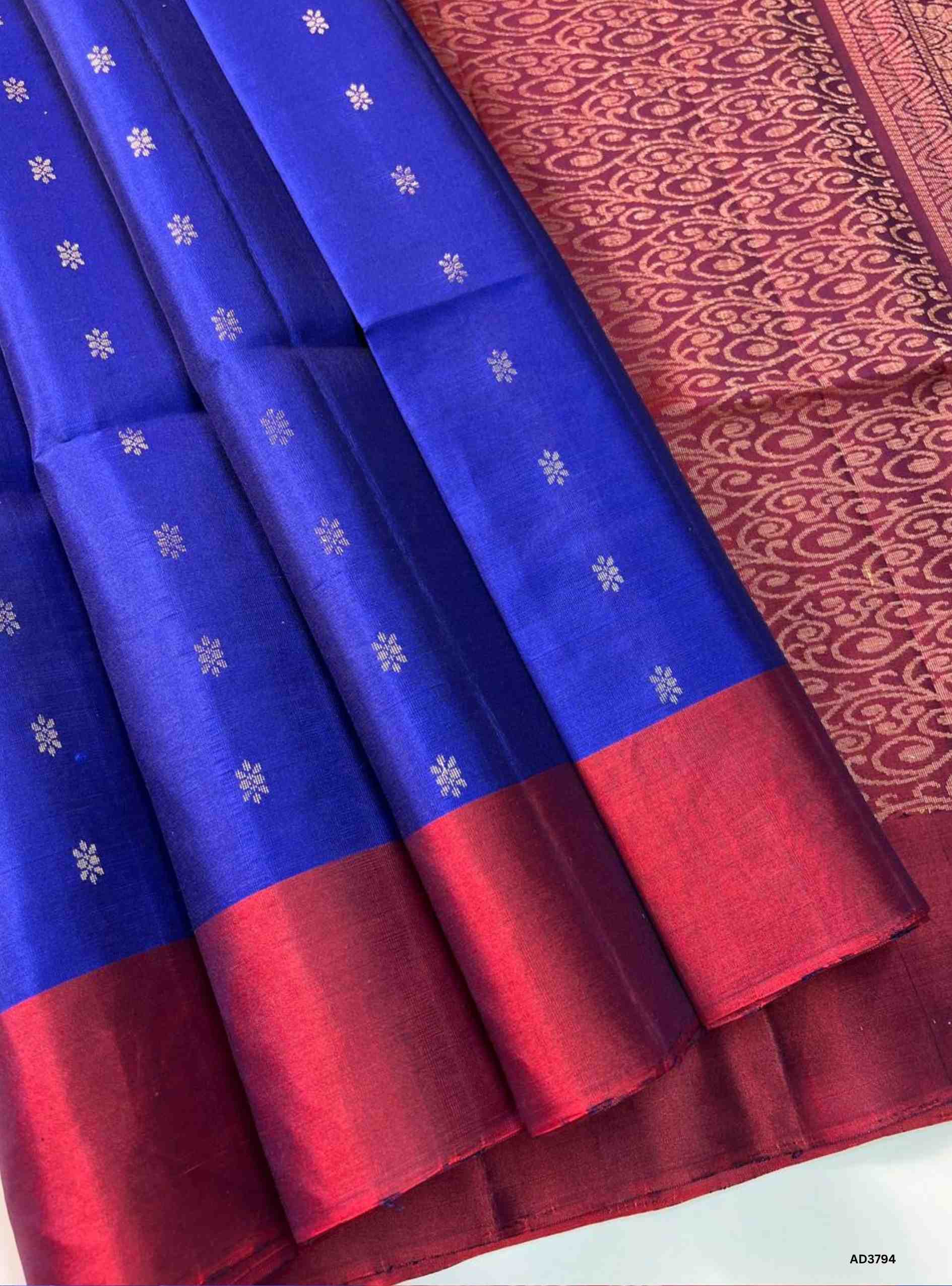 The Royal Blue & Maroon Bhutta Soft Silk Saree is a regal handwoven masterpiece crafted for festive elegance. The rich royal blue shade radiates sophistication and depth, while the maroon tone adds traditional warmth and auspicious charm. The bhutta weave, adorned with intricate motifs, enhances the saree’s texture and visual appeal. Pure gold zari on the border and pallu adds a shimmering finish, making this saree perfect for weddings, temple ceremonies, and cultural celebrations. A timeless jewel‑tone pai