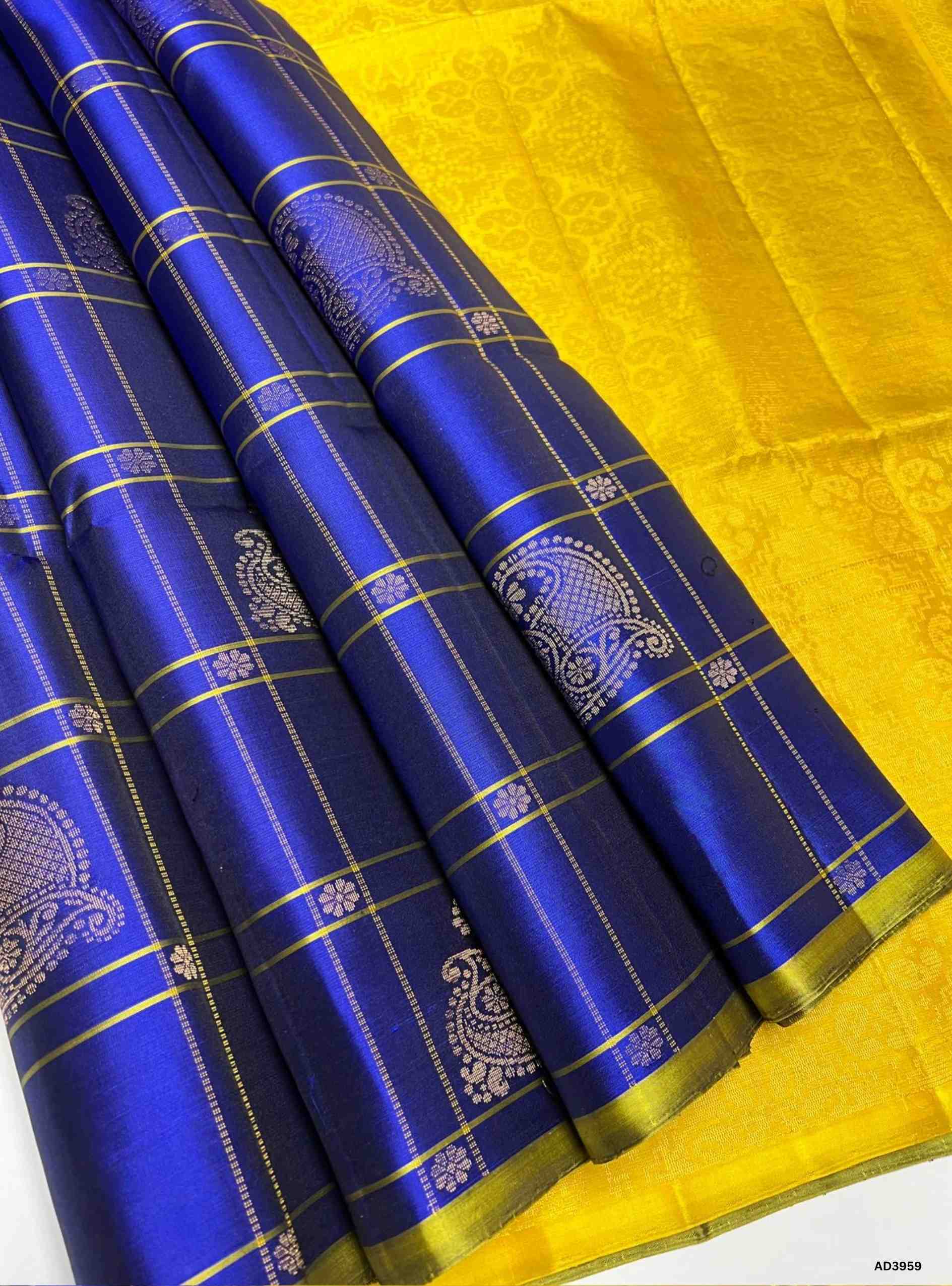 The Royal Blue & Yellow Checkered Bhutta Soft Silk Saree is a radiant handwoven creation that celebrates festive grandeur with a regal dual‑tone palette. The deep royal blue shade radiates sophistication and cultural richness, while the vibrant yellow adds auspicious brilliance and warmth. The checkered bhutta weave, adorned with delicate motifs, enhances the saree’s artistry, while zari highlights on the border and pallu lend a shimmering appeal. Perfect for weddings, temple ceremonies, and festive occasio