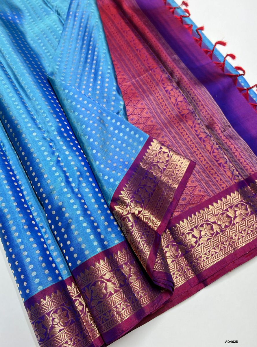 The Sky Blue & Magenta Kanchi Border Soft Silk Saree with 1000 Bhutta and Half Fine Tested Gold Zari is a radiant handwoven creation that unites serene elegance with festive vibrance, making it perfect for weddings, temple ceremonies, and cultural celebrations.