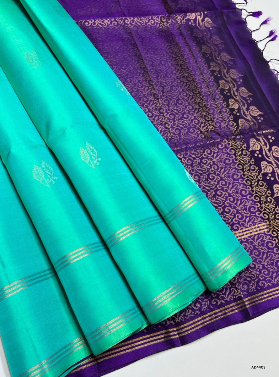 The Turquoise & Purple Soft Silk Saree with Bhutta motifs is a radiant handwoven creation that embodies festive charm and cultural richness. The turquoise shade conveys serenity, vibrance, and celebratory freshness, while the purple contrast adds regal depth, devotion, and timeless elegance. The bhutta motifs woven across the body enhance its traditional appeal, while zari borders and pallu lend grandeur. Perfect for weddings, temple ceremonies, and festive occasions, this saree reflects South Indian crafts