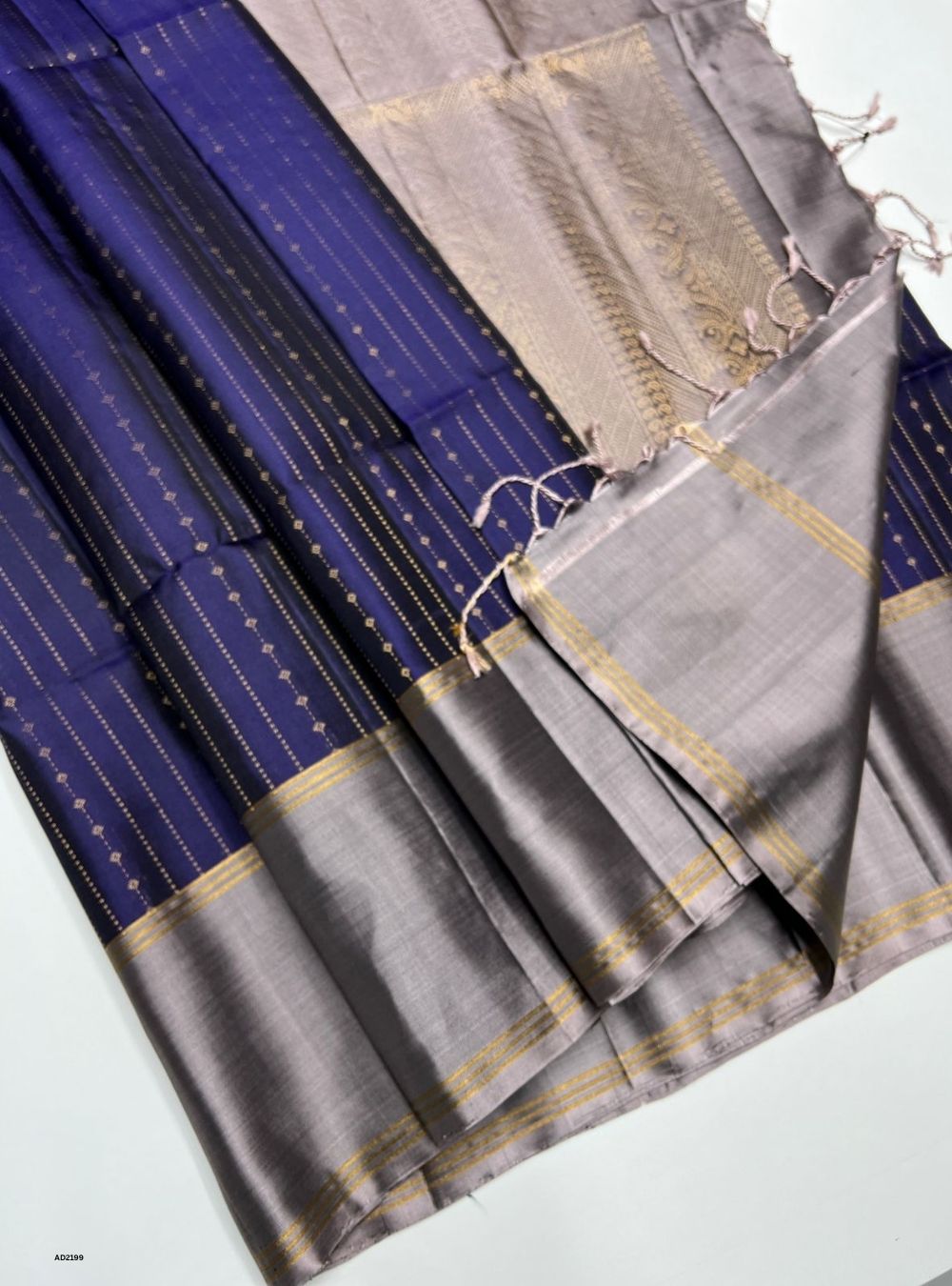 Two sarees, one blue and one gray with gold borders, on a white background.