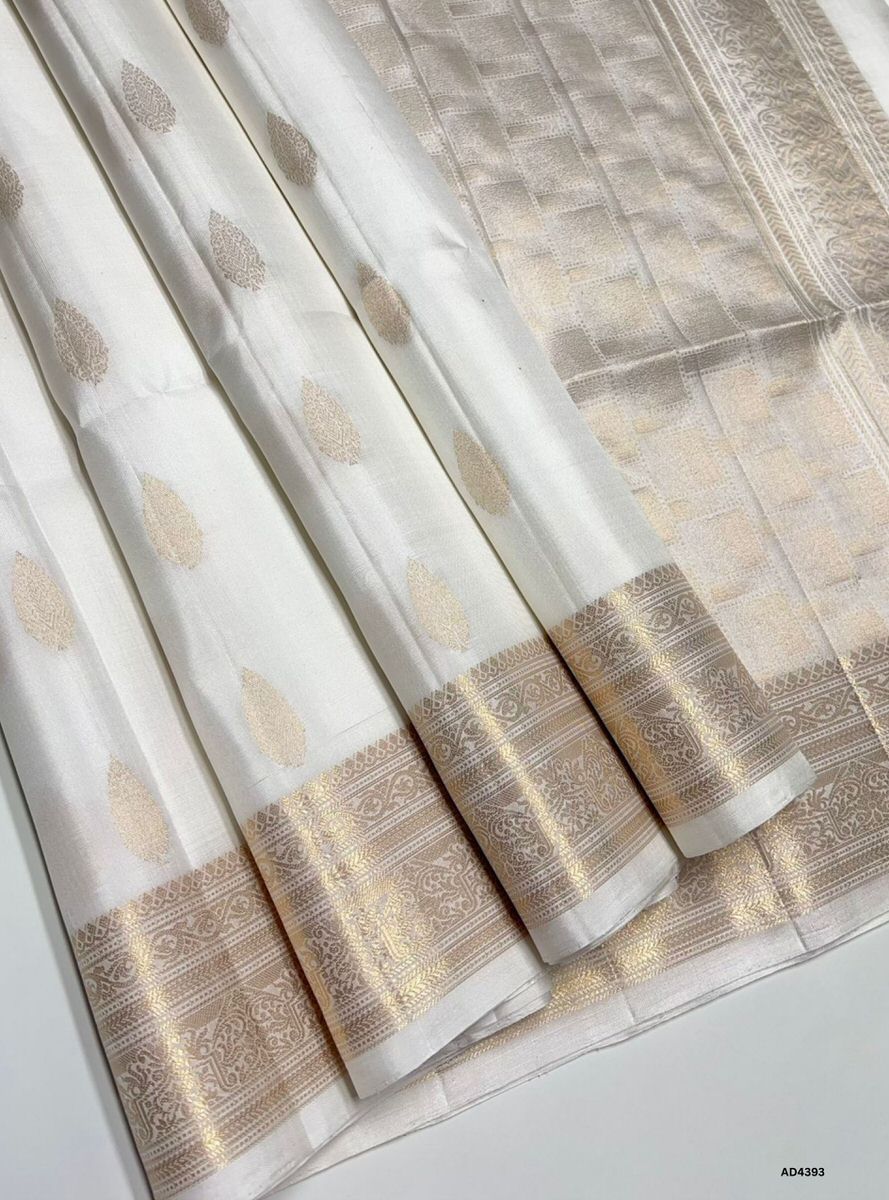 The White Kanchi Border Soft Silk Saree is a pristine handwoven creation that radiates purity, devotion, and timeless elegance. The white shade symbolizes serenity, auspiciousness, and spiritual grace, while the temple‑inspired Kanchi border enriched with pure gold zari elevates its grandeur. With its lustrous drape and coordinated blouse, this saree is perfect for weddings, temple ceremonies, and cultural gatherings. A true testament to Kanchipuram weaving, it blends classic simplicity with heritage artist