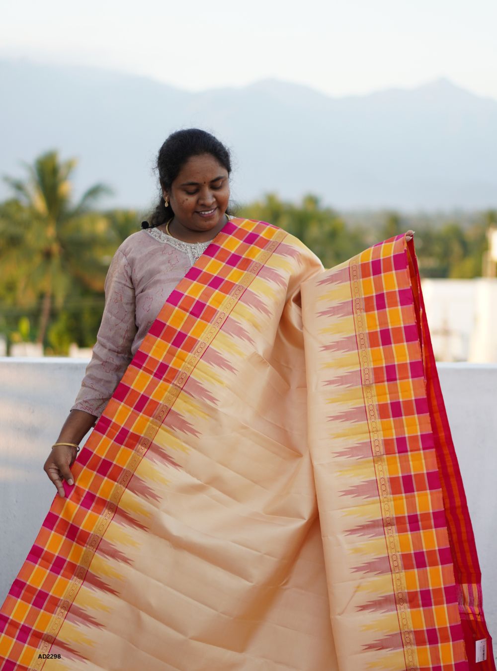Woman holding a colorful saree with a scenic background