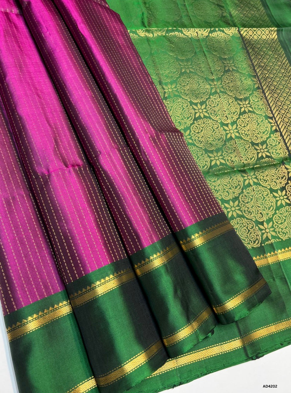 
The Magenta & Green Vairaoosi X Retta Pet Soft Silk Saree is a striking handwoven creation that unites two iconic motifs of Kanchipuram weaving. The magenta shade conveys vibrance, devotion, and festive charm, while the green adds prosperity, freshness, and celebratory brilliance. The body features the Vairaoosi diamond motif, symbolizing wealth and auspiciousness, while the Retta Pet double line temple border enriches the saree with timeless heritage. Enhanced with pure gold zari and a lustrous drape, thi