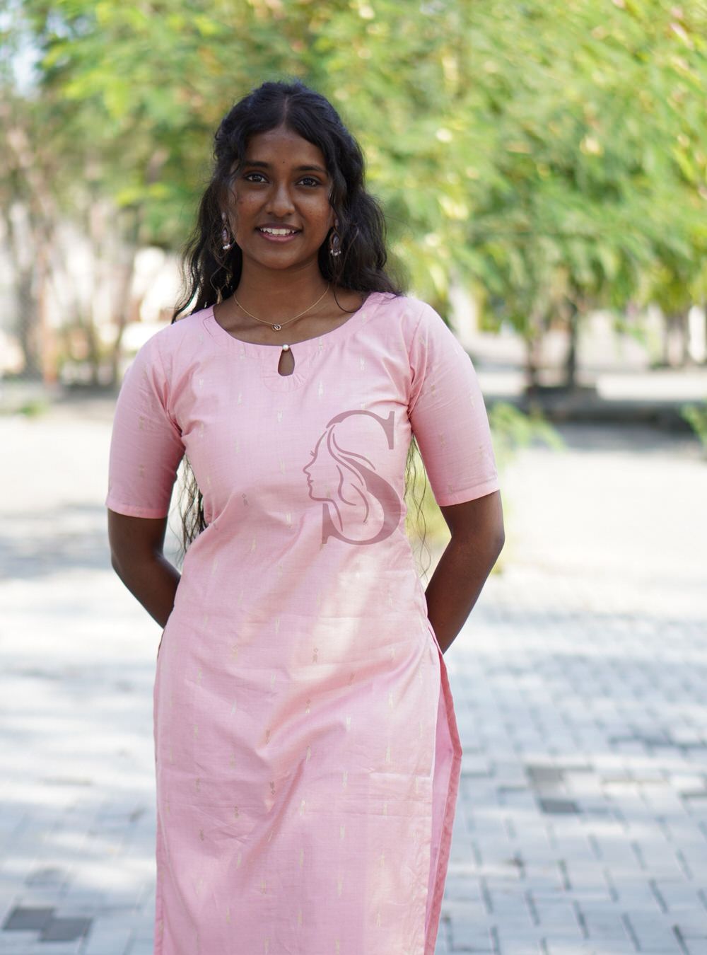 Woman wearing a pink dress with a face design outdoors
