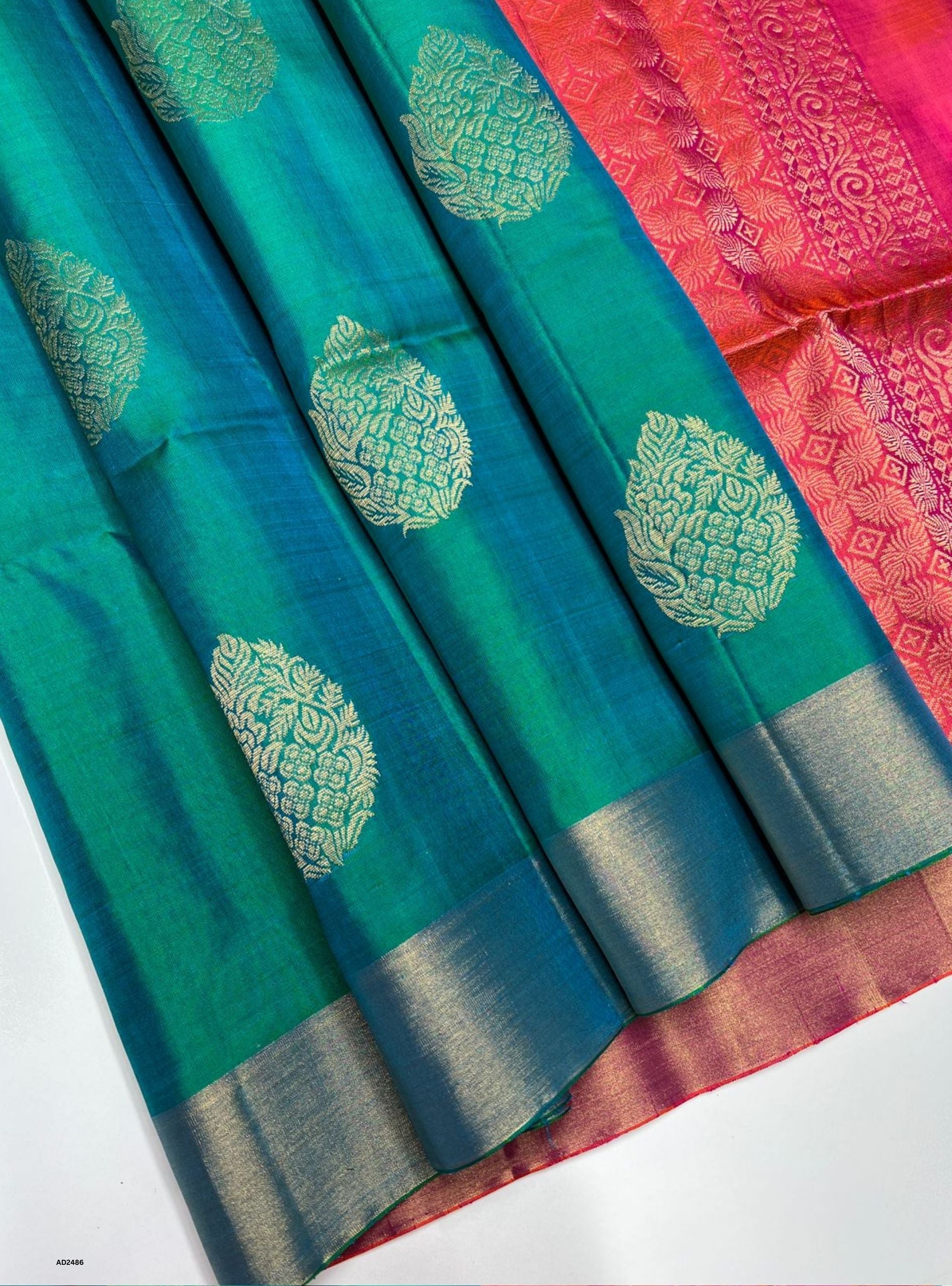 Teal saree with green floral patterns and pink saree with geometric pattern on a white background