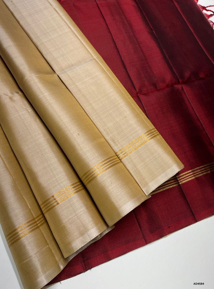 The Beige & Maroon Plain Soft Silk Saree with Pure Gold Zari is a graceful handwoven creation that radiates understated charm and festive richness, making it ideal for weddings, temple ceremonies, and cultural occasions.