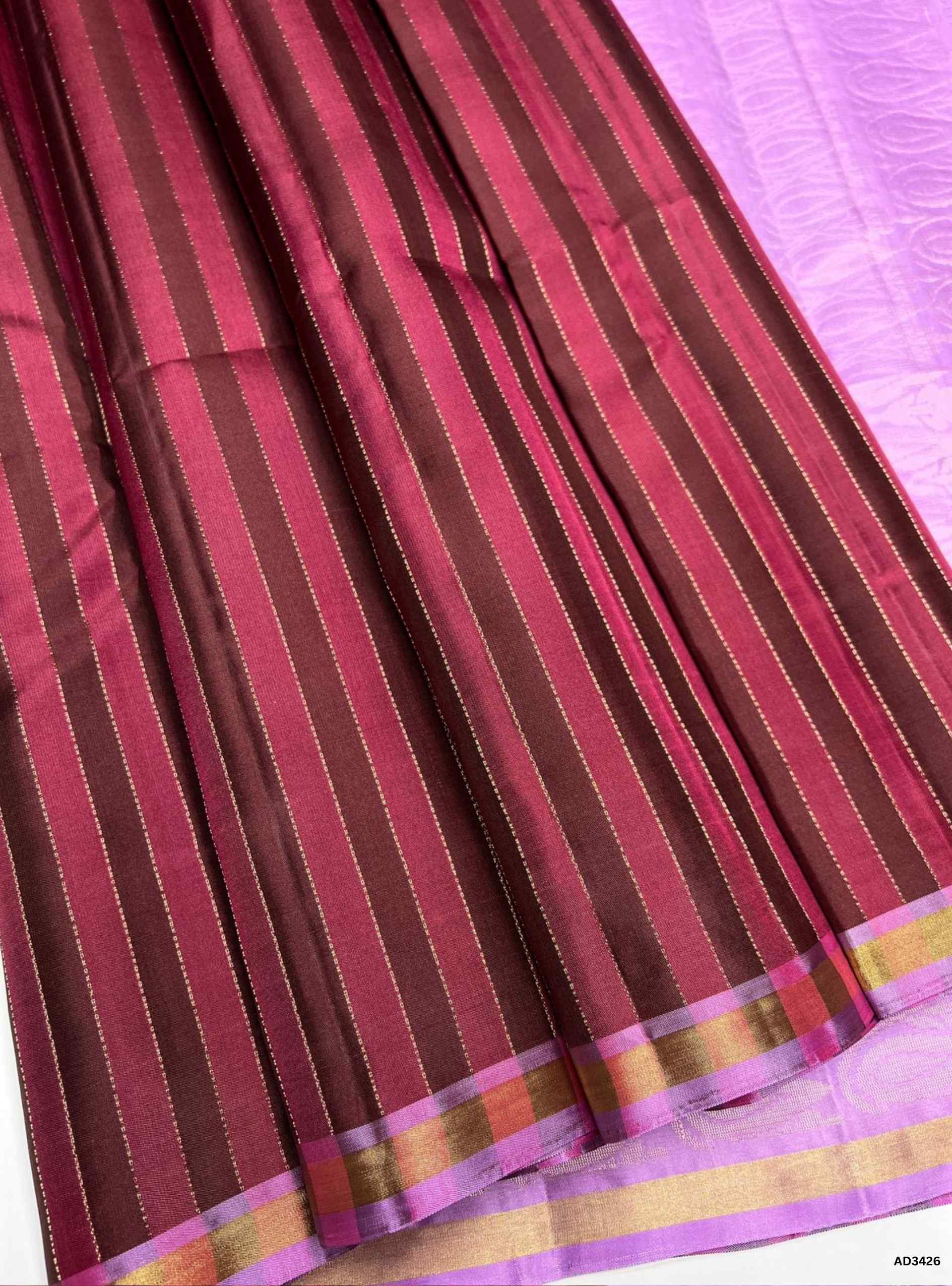 The Brown & Lavender Soft Silk Saree brings together the richness of handwoven bhutta motifs with the elegance of a jacquard border, enhanced by a shimmering lavender pallu that adds a graceful contrast to the deep brown body.