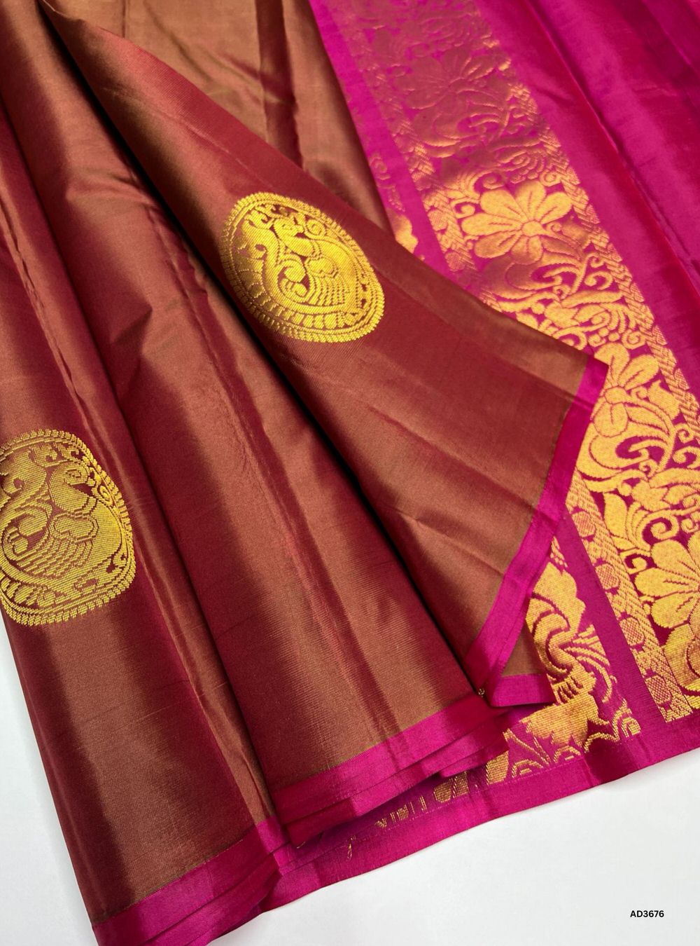 The Brown & Pink Soft Silk Saree is a striking handwoven creation featuring a rich brown body adorned with Mayil circular bhutta motifs in shimmering zari. Its radiant pink border and pallu highlight the intricate Kanchi style border, adding grandeur and traditional charm. Perfect for weddings, festive occasions, and cultural gatherings, this saree blends motif artistry with timeless Kanchi craftsmanship.