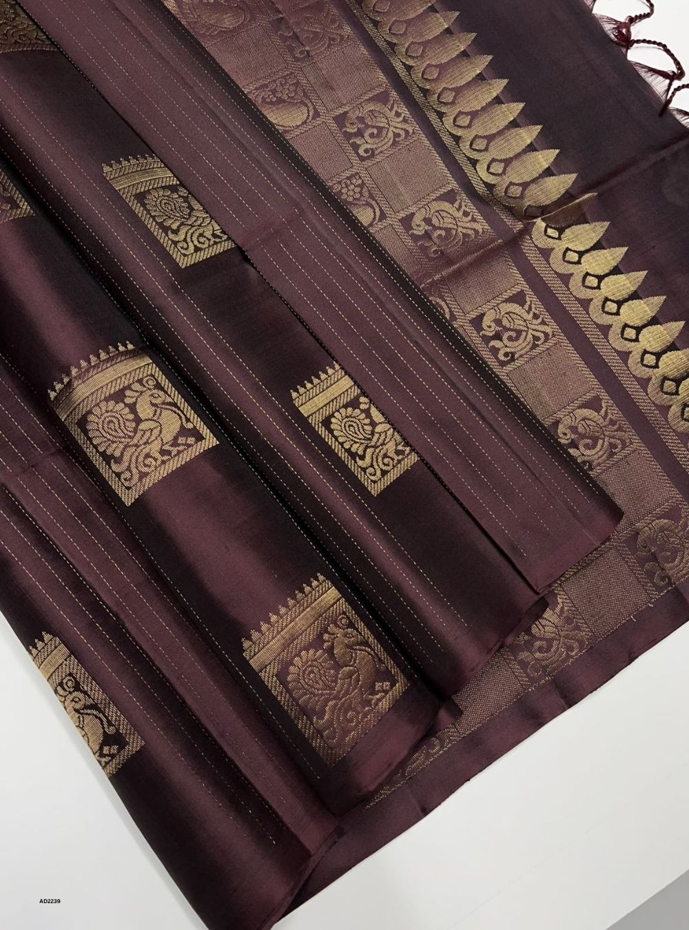 Brown saree with gold patterns on a white background