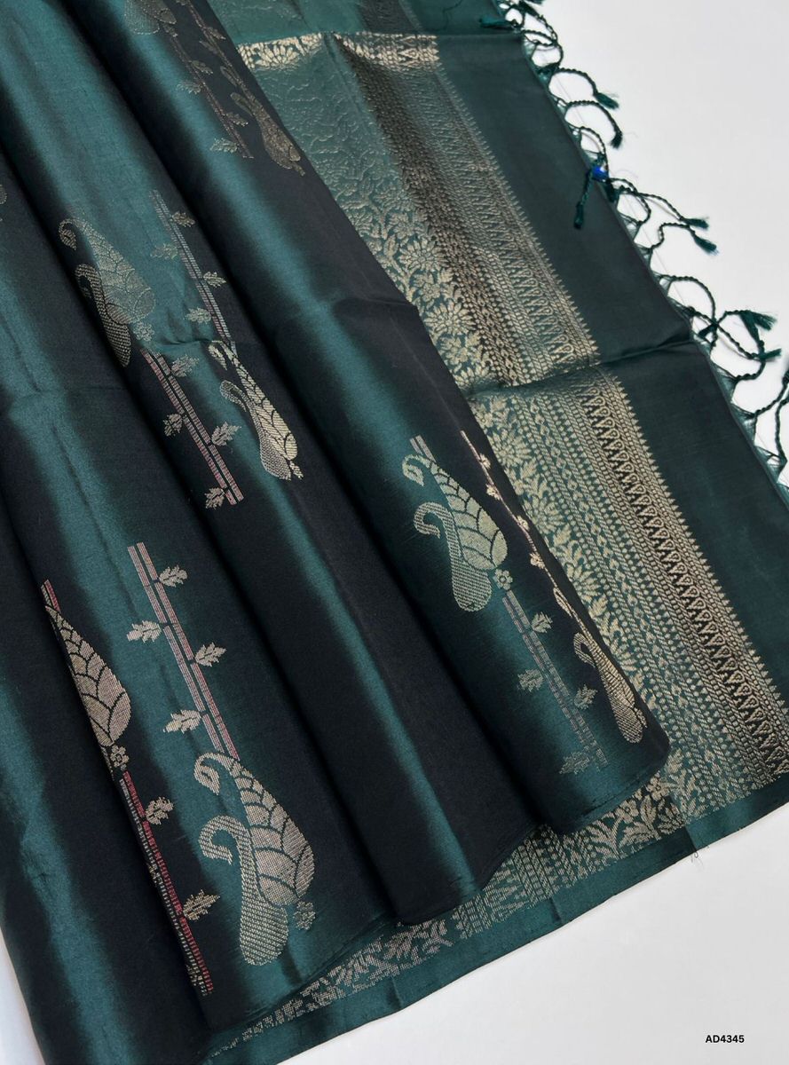 The Dark Green Fancy Bhutta Soft Silk Saree is a majestic handwoven creation that radiates festive grandeur and cultural richness. The deep dark green shade symbolizes prosperity, devotion, and auspicious charm, while the fancy bhutta motifs add ornamental artistry and intricate detailing. Enhanced with pure gold zari borders and a lustrous drape, this saree is perfect for weddings, temple ceremonies, and celebratory occasions. A timeless masterpiece, it blends jewel‑tone depth with motif‑centric weaving he