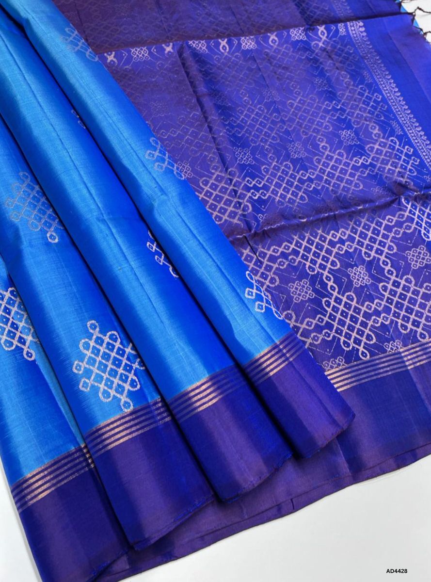The Dual Tone Blue & Ink Blue Kolam Soft Silk Saree with Pure Gold Zari is a majestic handwoven creation that unites serene brilliance with regal depth, making it ideal for weddings, temple ceremonies, and festive occasions.