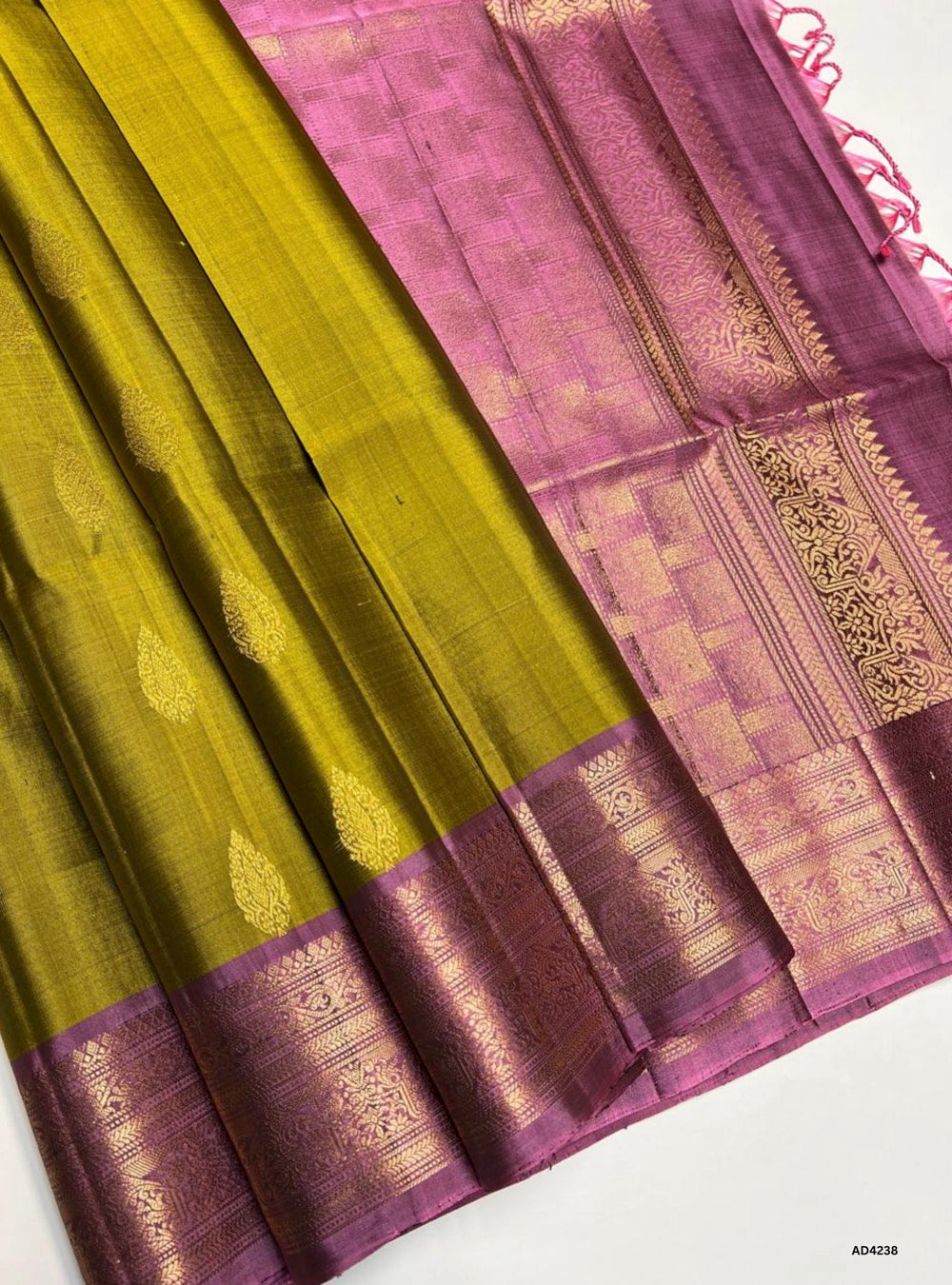 The Fenugreek & Rosewood Kanchi Border Soft Silk Saree is a heritage handwoven creation that radiates earthy elegance and cultural grandeur. The fenugreek shade conveys prosperity, warmth, and festive charm, while the rosewood tone adds depth, richness, and timeless sophistication. Enhanced with temple‑inspired Kanchi borders and pure gold zari detailing, this saree is perfect for weddings, temple ceremonies, and festive occasions. A timeless piece of artistry, it blends natural vibrance with the grandeur o