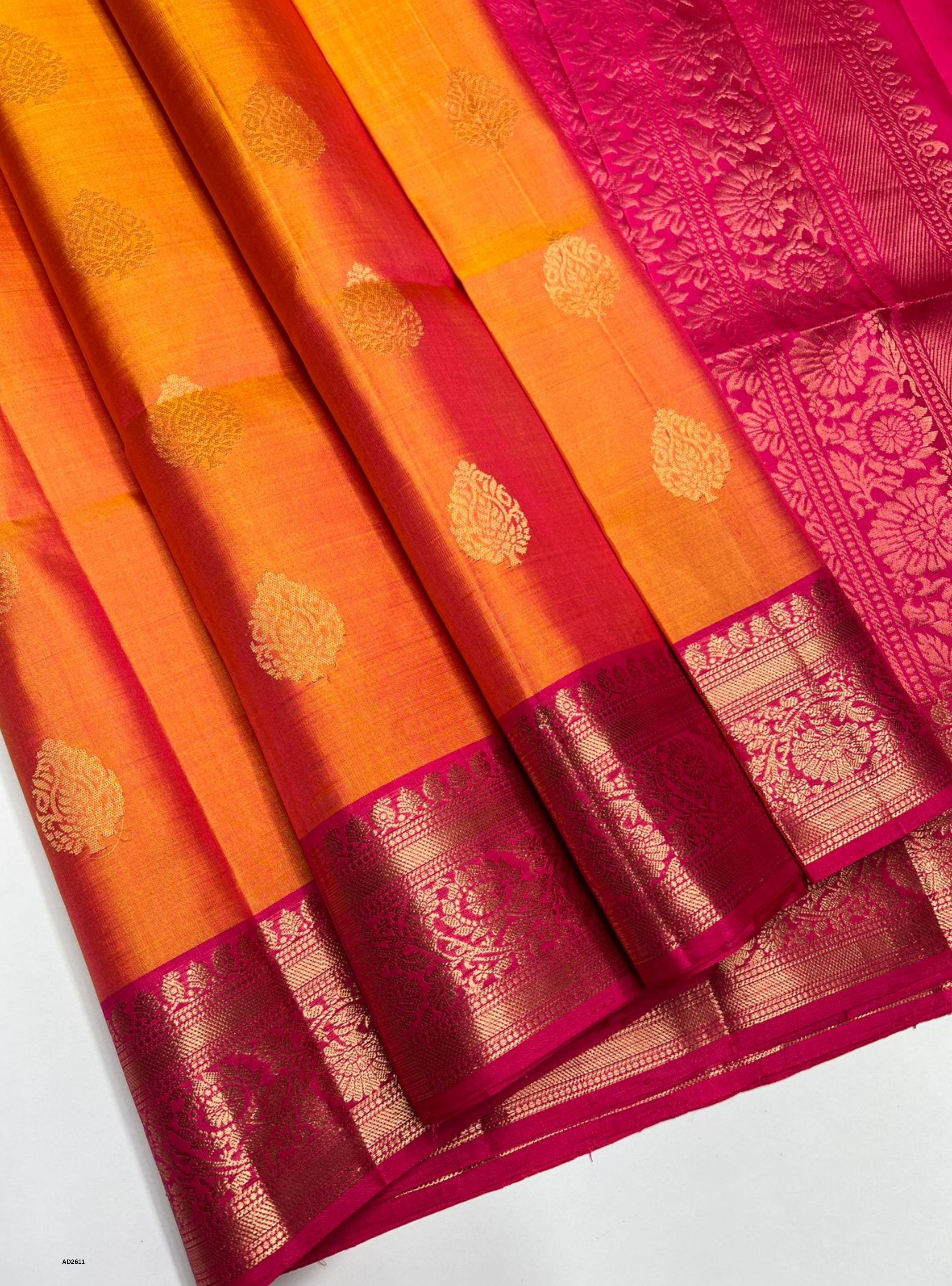 Orange and pink saree with intricate patterns on a white background