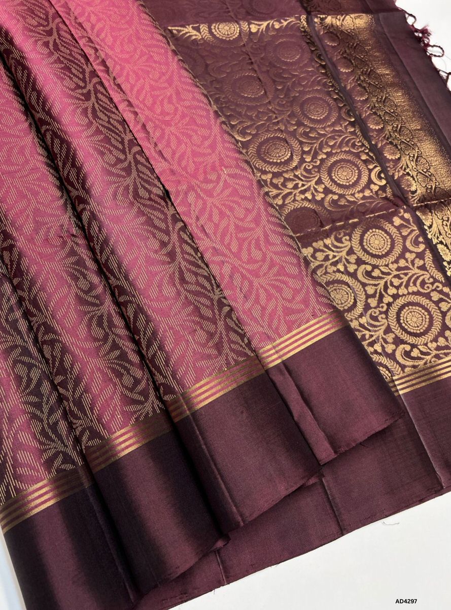 The Jam & Coffee Brown Bridal Soft Silk Saree is a regal handwoven masterpiece that radiates cultural richness and bridal elegance. The jam shade conveys devotion, prosperity, and jewel‑tone brilliance, while the coffee brown contrast adds earthy depth and heritage grandeur. Enhanced with pure gold zari, temple‑inspired borders, and intricate bridal motifs, this saree is perfect for weddings, temple ceremonies, and festive occasions. A timeless creation, it blends vibrant artistry with traditional South Ind