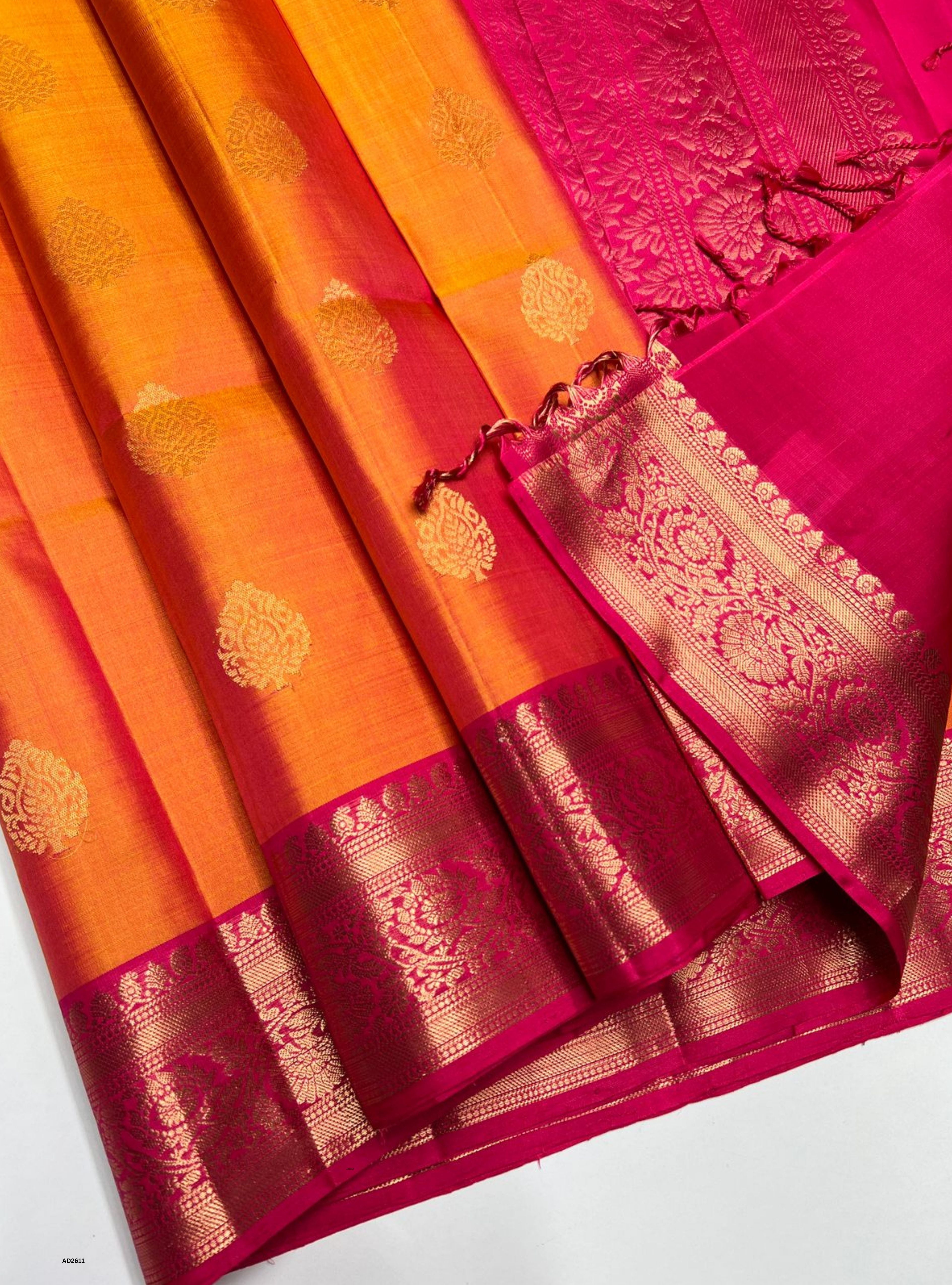 Orange and pink saree with intricate patterns on a white background