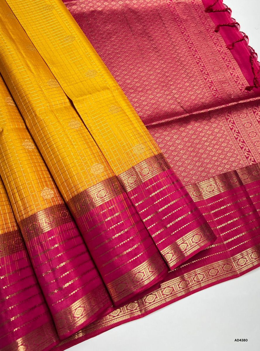 The Mango Yellow & Rani Pink Checkered Retta Pet Soft Silk Saree is a radiant handwoven creation that celebrates festive charm and cultural richness. The mango yellow shade conveys joy, prosperity, and auspicious brilliance, while the rani pink checks add regal vibrance and heritage depth. Enhanced with pure gold zari borders and a lustrous drape, this saree is perfect for weddings, temple ceremonies, and celebratory occasions. A timeless masterpiece, it blends vibrant dual tones with the traditional Retta 