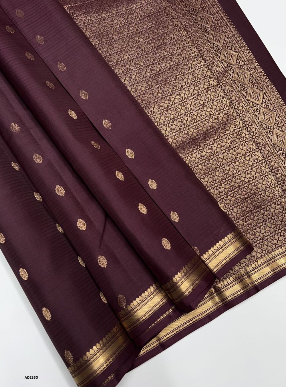 Maroon saree with gold patterns on a white background