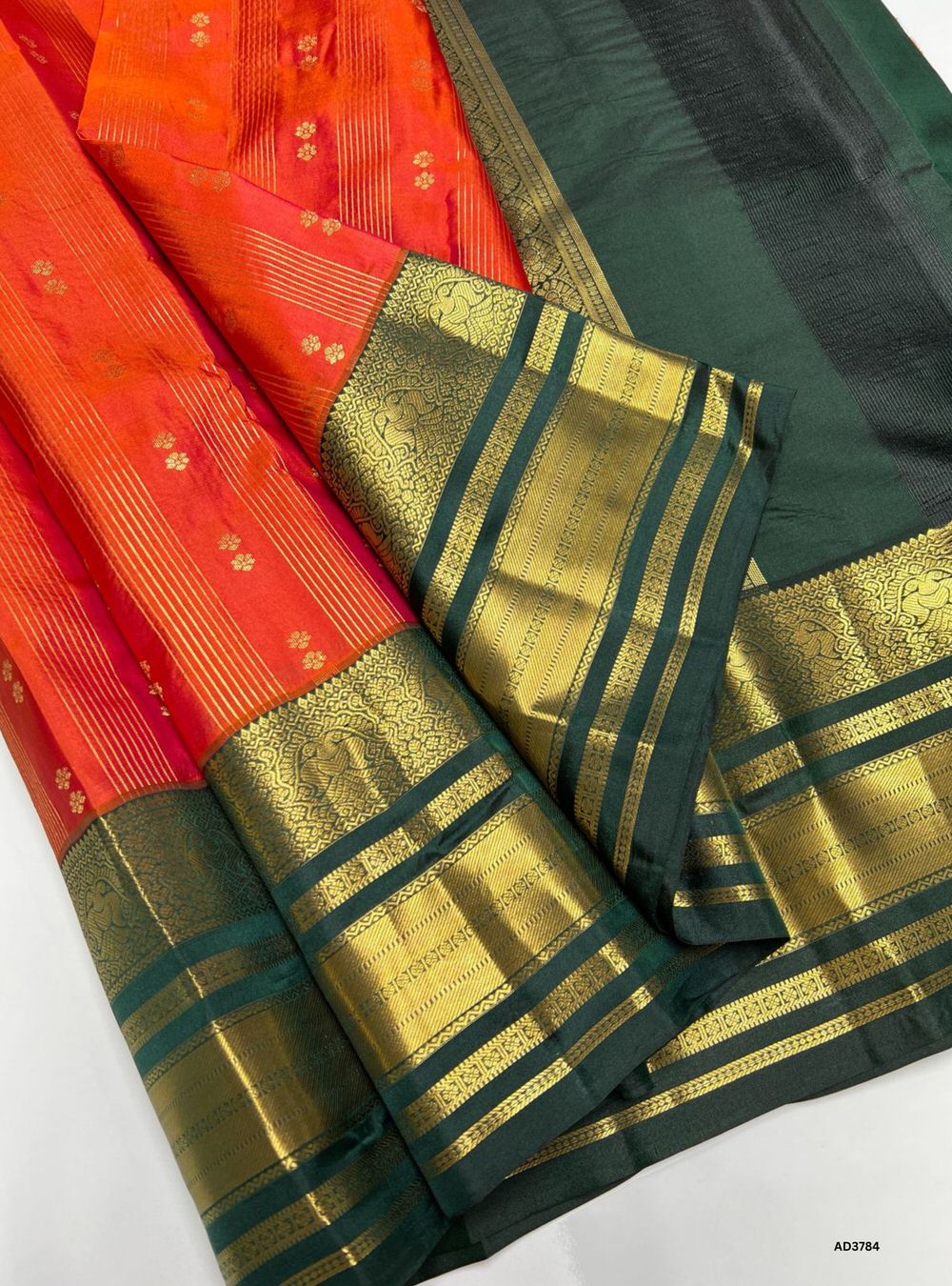 The Orange & Dark Green Kanjeevaram Silk Saree is a majestic handwoven creation featuring a radiant orange body paired with a deep dark green border. Its traditional Kanjeevaram weave and pure gold zari detailing highlight the grandeur of South Indian craftsmanship. Perfect for weddings, temple ceremonies, and festive occasions, this saree embodies cultural richness and timeless elegance.