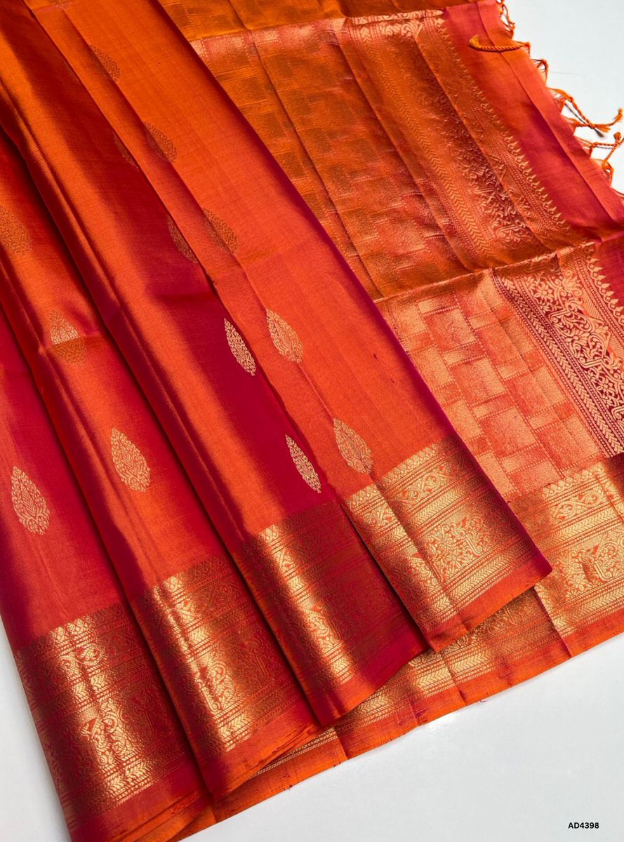 The Orangish Pink Kanchi Border Soft Silk Saree is a radiant handwoven creation that embodies festive charm and cultural richness. The orangish pink shade conveys joy, femininity, and celebratory warmth, while the temple‑inspired Kanchi border enriched with pure gold zari elevates its grandeur. With its lustrous drape and coordinated blouse, this saree is perfect for weddings, temple ceremonies, and festive occasions. A timeless masterpiece, it blends pastel vibrance with the heritage of Kanchipuram weaving