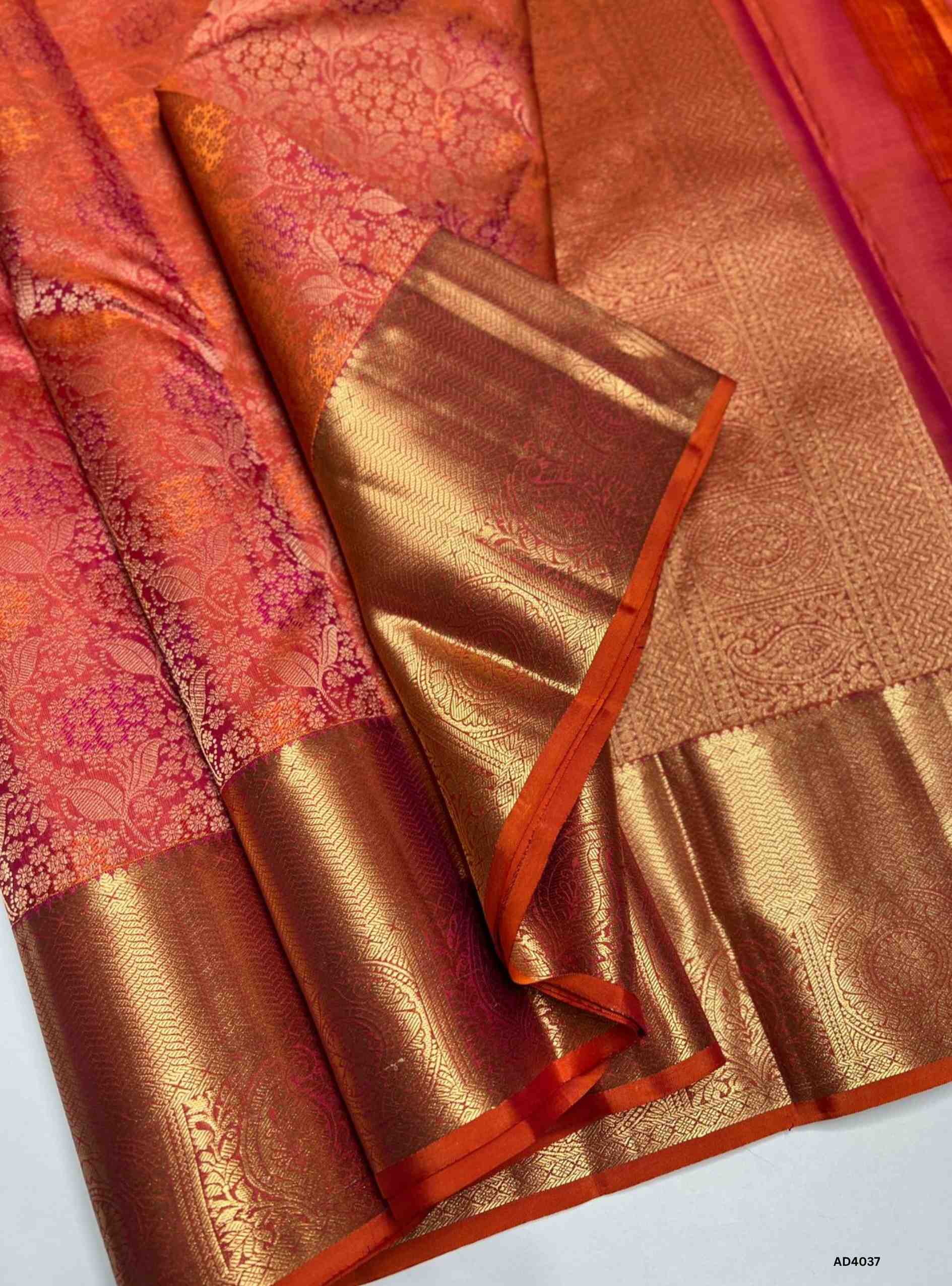 The Orangish Pink Kanjeevaram Bridal Soft Silk Saree is a radiant handwoven masterpiece crafted for weddings and auspicious occasions. The unique orangish pink shade symbolizes joy, prosperity, and feminine grace, making it a standout bridal choice. Its lustrous drape is enriched with heavy gold zari, temple‑inspired borders, and a grand pallu featuring motifs of peacocks, lotuses, and traditional geometric artistry. This saree embodies the heritage of Kanchipuram weaving, combining elegance with cultural g
