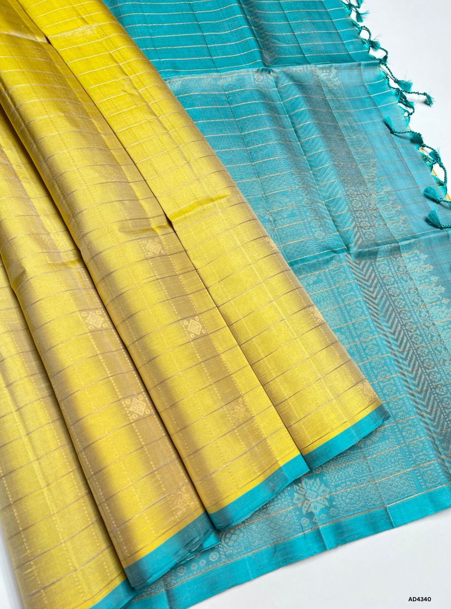 The Pastel Yellow & Ice Blue Checkered Soft Silk Saree is a refreshing handwoven creation that radiates elegance and cultural charm. The pastel yellow shade conveys joy, warmth, and festive brightness, while the ice blue checks add serenity, freshness, and modern sophistication. Enhanced with pure gold zari borders and a lustrous drape, this saree is perfect for weddings, temple ceremonies, and celebratory occasions. A timeless masterpiece, it blends pastel vibrance with heritage checkered artistry.
