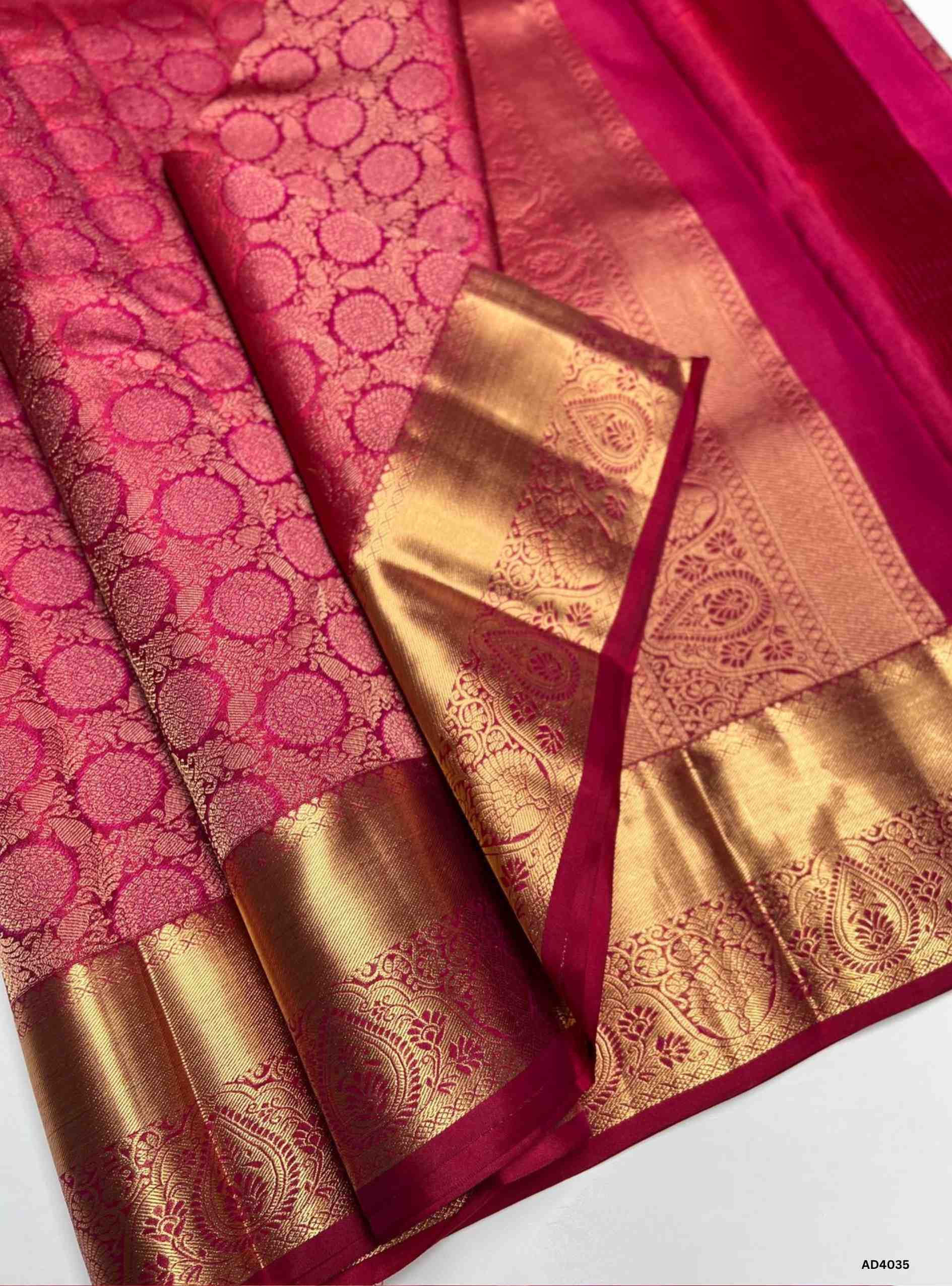 The Rani Pink Kanjeevaram Bridal Soft Silk Saree is a radiant handwoven masterpiece crafted for weddings and auspicious occasions. The vibrant rani pink shade symbolizes joy, prosperity, and feminine grace, making it a timeless bridal choice. Its lustrous drape is enriched with heavy gold zari, temple‑inspired borders, and a grand pallu featuring motifs of peacocks, lotuses, and traditional geometric artistry. This saree embodies the heritage of Kanchipuram weaving, combining elegance with cultural grandeur
