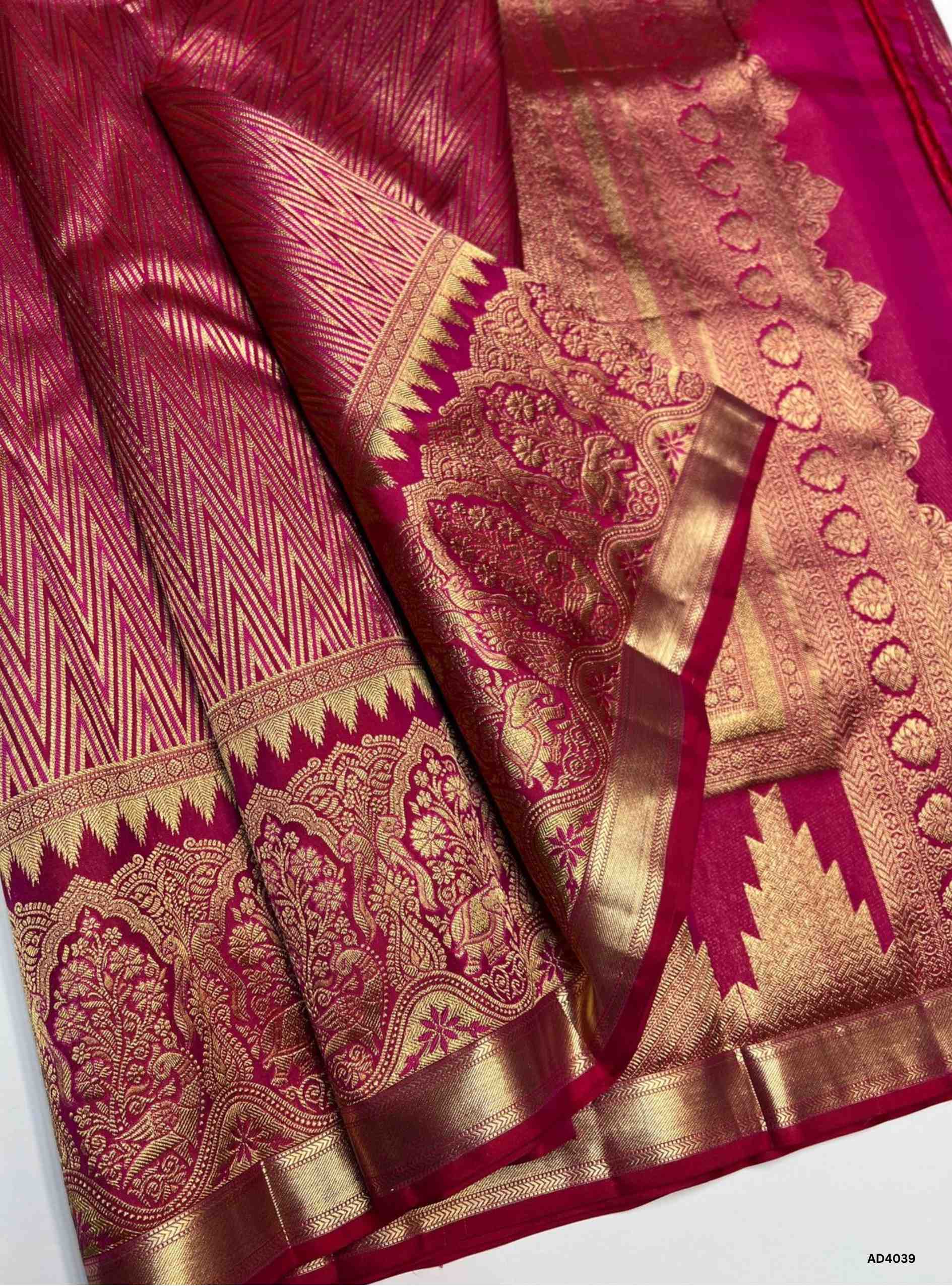 The Rani Pink Kanjeevaram Bridal Soft Silk Saree is a majestic handwoven masterpiece designed for weddings and grand occasions. The vibrant rani pink shade symbolizes joy, prosperity, and auspicious brilliance, making it a timeless bridal choice. Its lustrous drape is enriched with heavy gold zari, temple‑inspired borders, and a grand pallu featuring traditional motifs of peacocks, lotuses, and geometric artistry. This saree embodies the heritage of Kanchipuram weaving, combining elegance with cultural gran