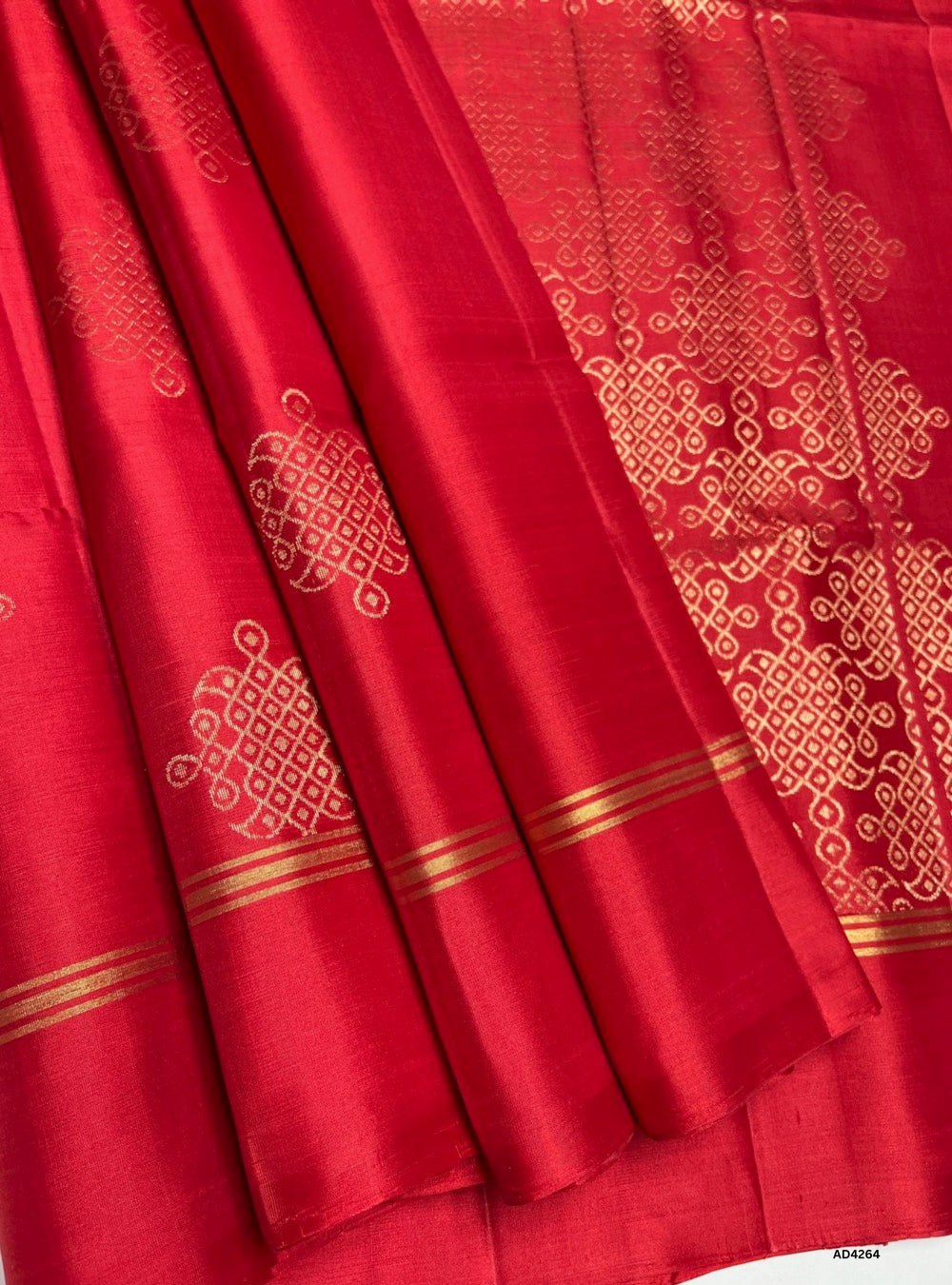 The Red Kolam Soft Silk Saree is a striking handwoven creation that radiates auspiciousness and festive grandeur. The bold red shade symbolizes prosperity, celebration, and timeless elegance, making it a perfect choice for weddings and temple ceremonies. Inspired by traditional South Indian Kolam artistry, the border and pallu are adorned with intricate motifs woven in pure gold zari, reflecting cultural richness and heritage. With its lustrous drape and vibrant palette, this saree embodies the essence of K